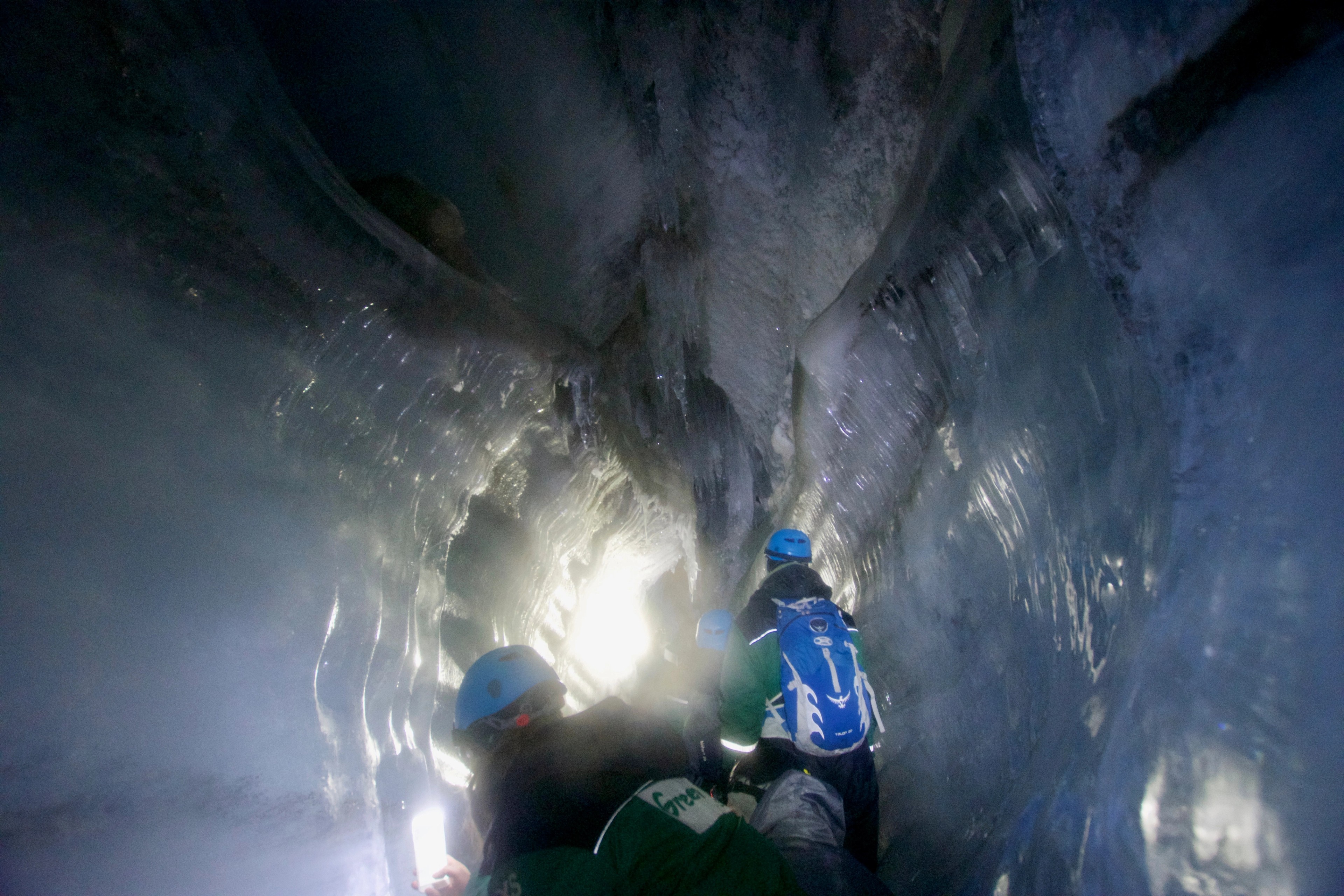A person explores a blue-lit ice cave.