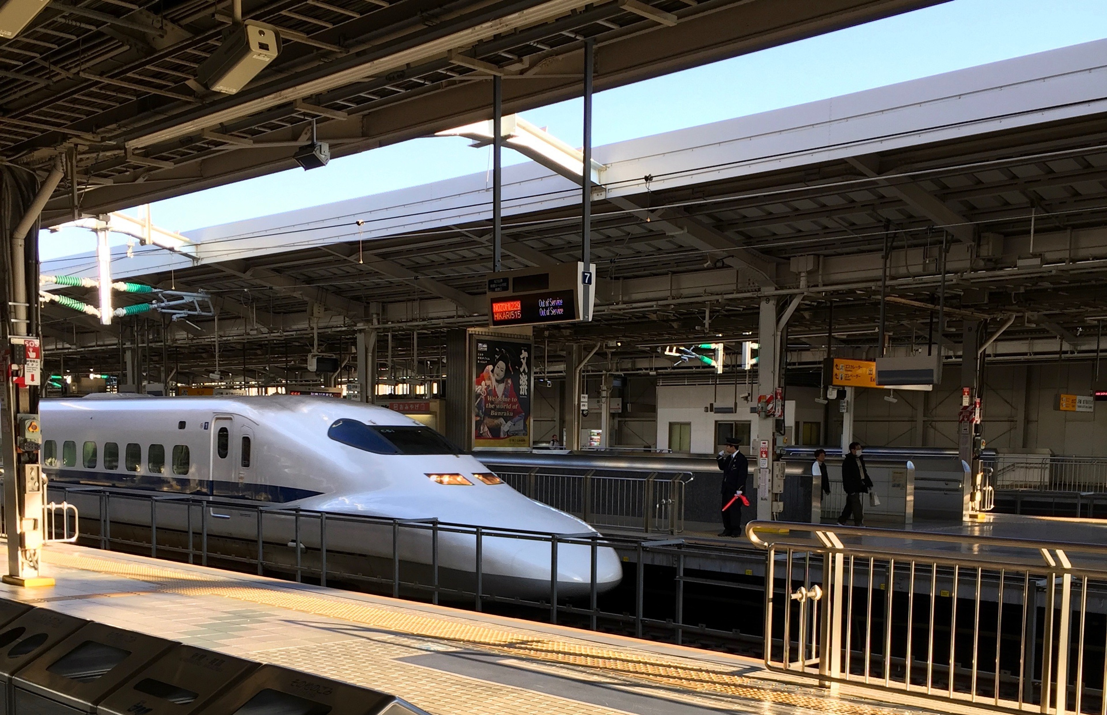 A Shinkansen train is seen at the station beneath a broad metal roof.