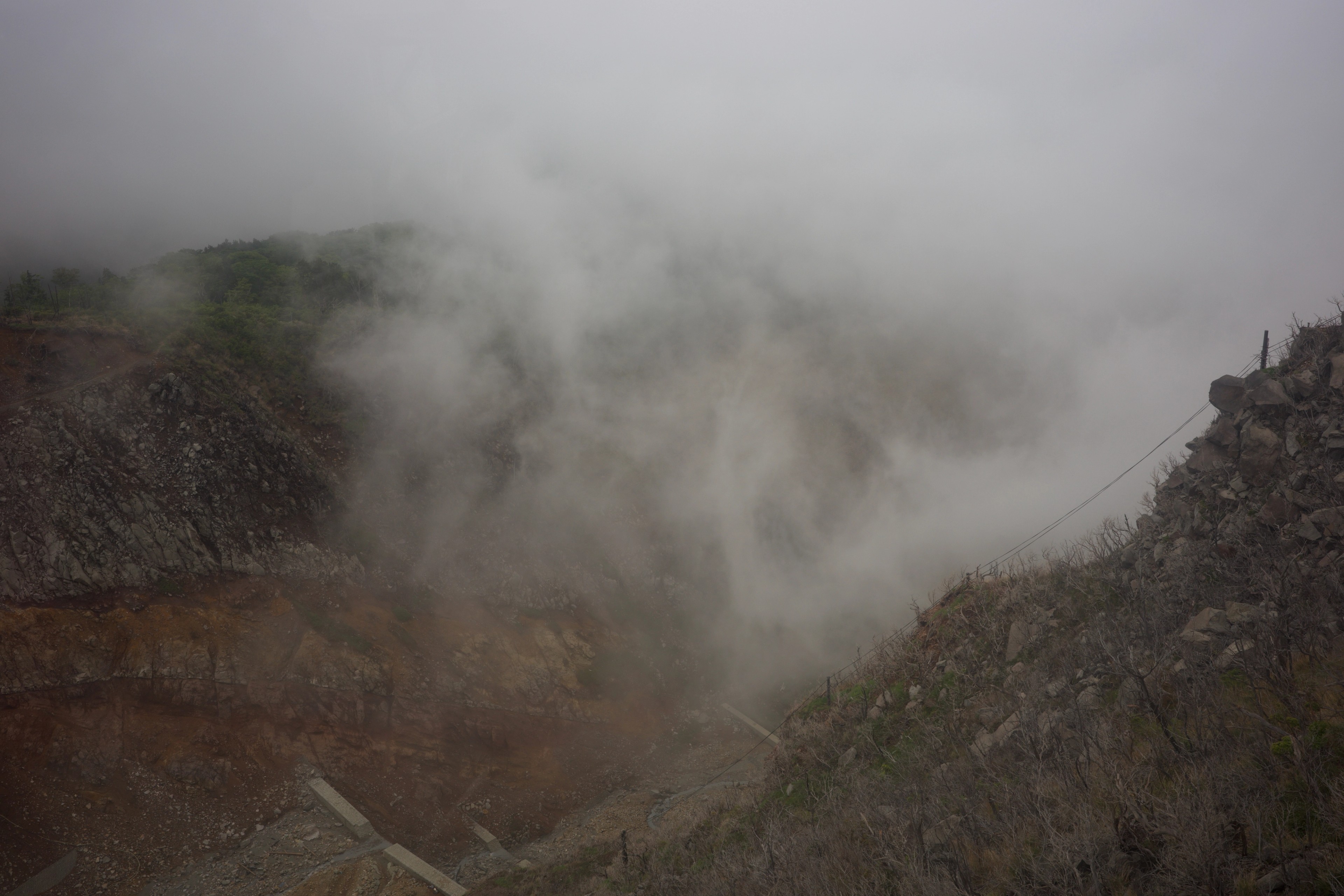 Steam rises from a rocky geothermal slope.