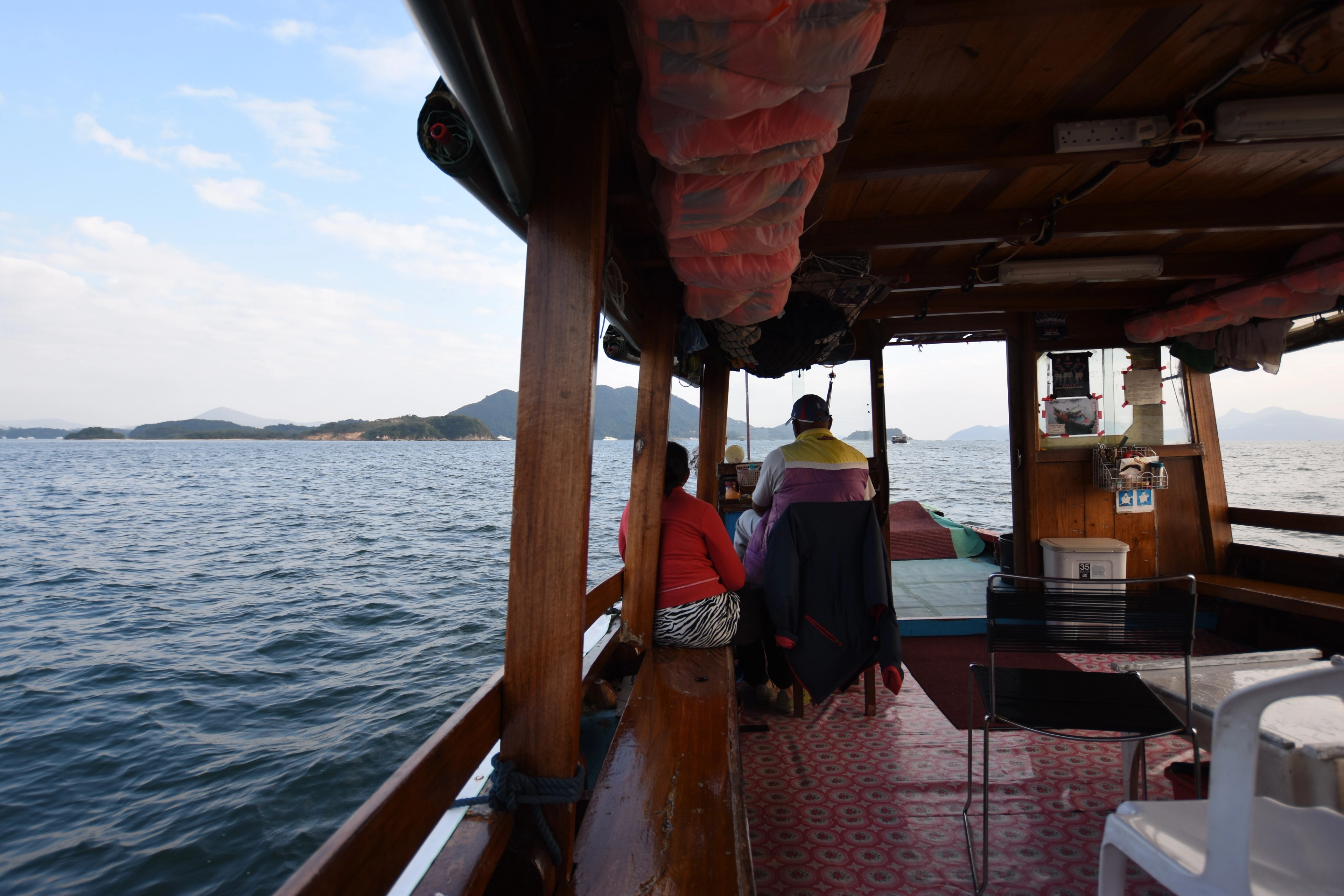 Passengers look out from inside a covered boat on the water.