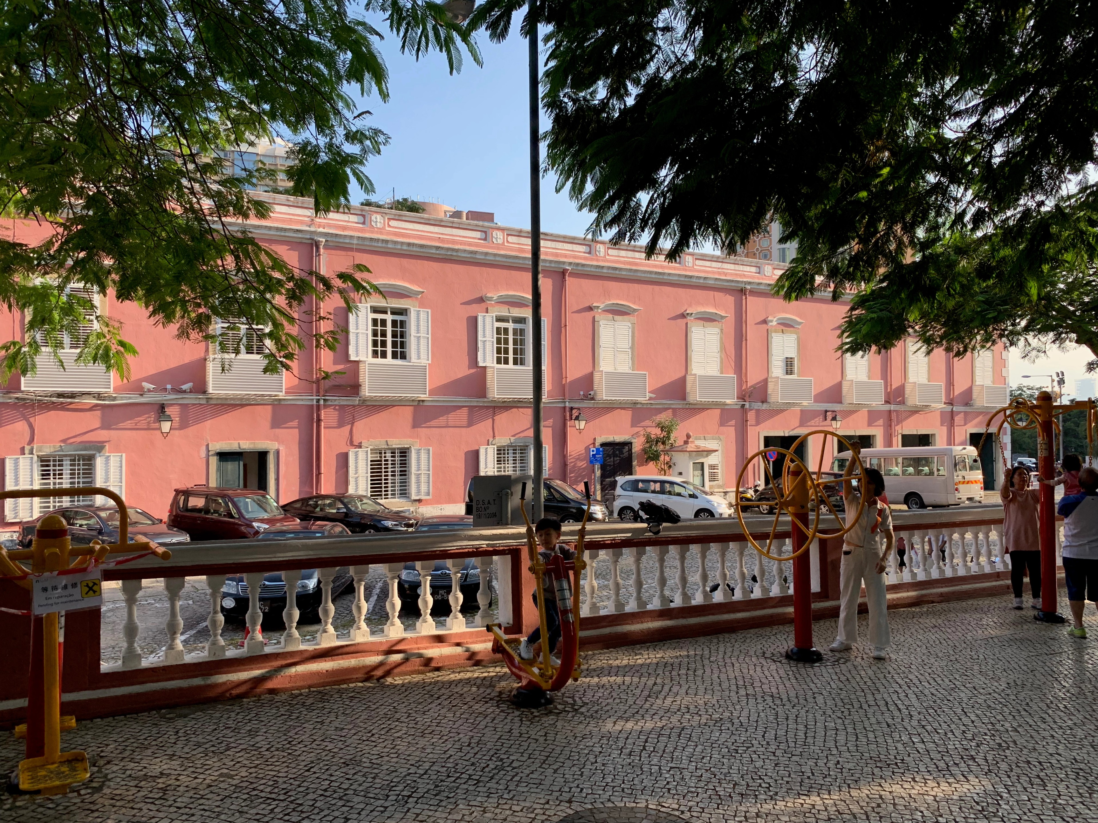 Pink colonial-era building beside the Macau waterfront and bridge.