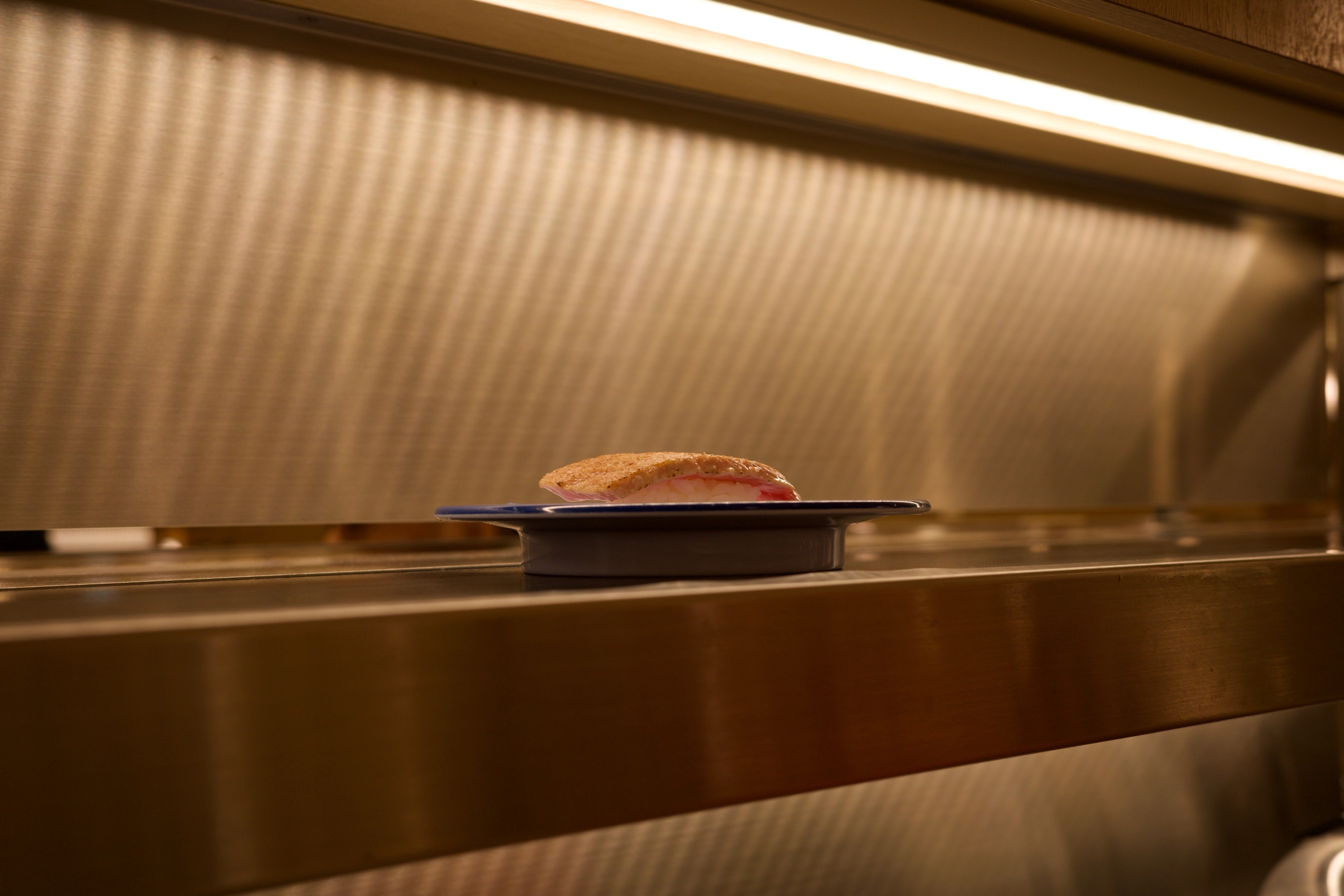 A plate of sushi sits on a wooden counter.