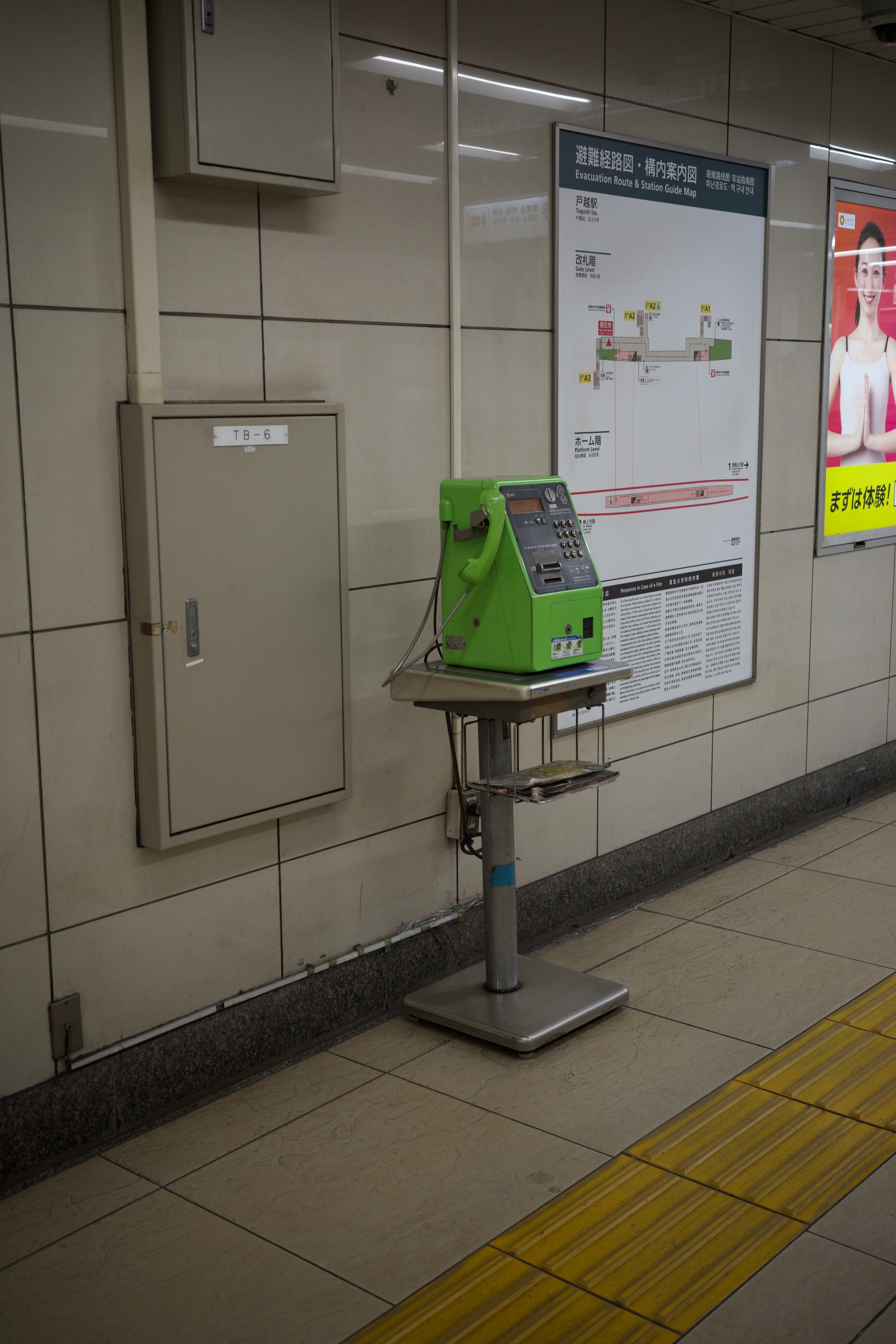 A subway station wall with a route map and a green cleaning cart.