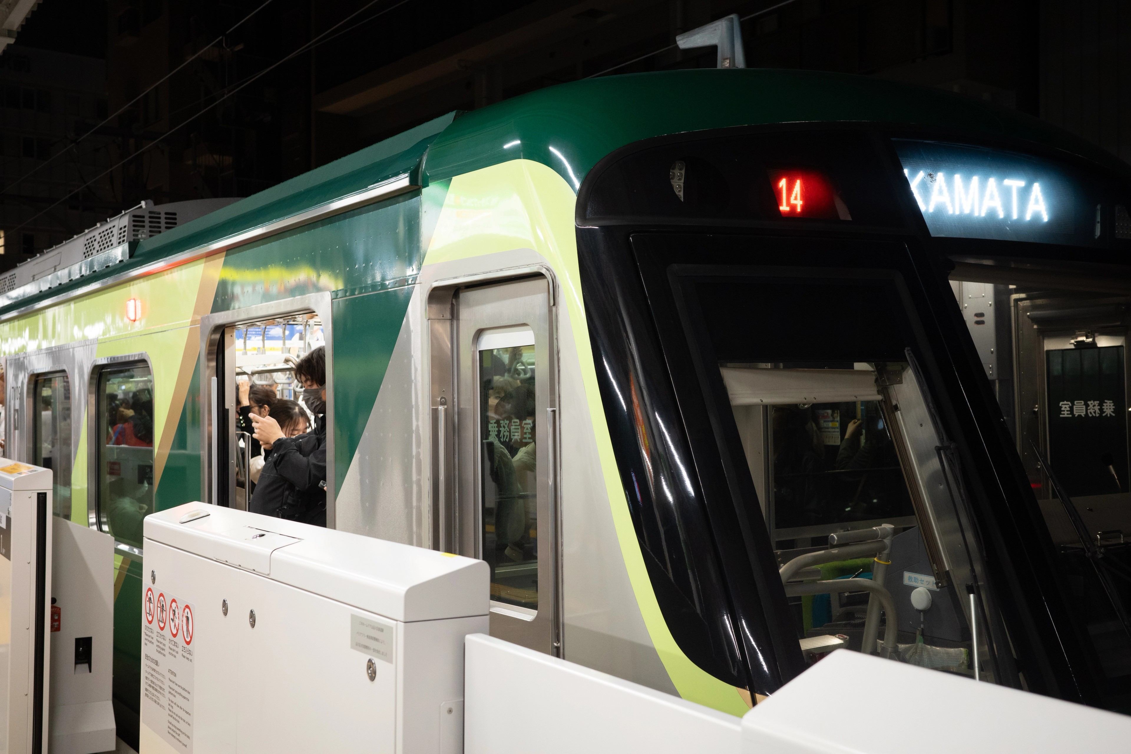 A green commuter train waits at a station.