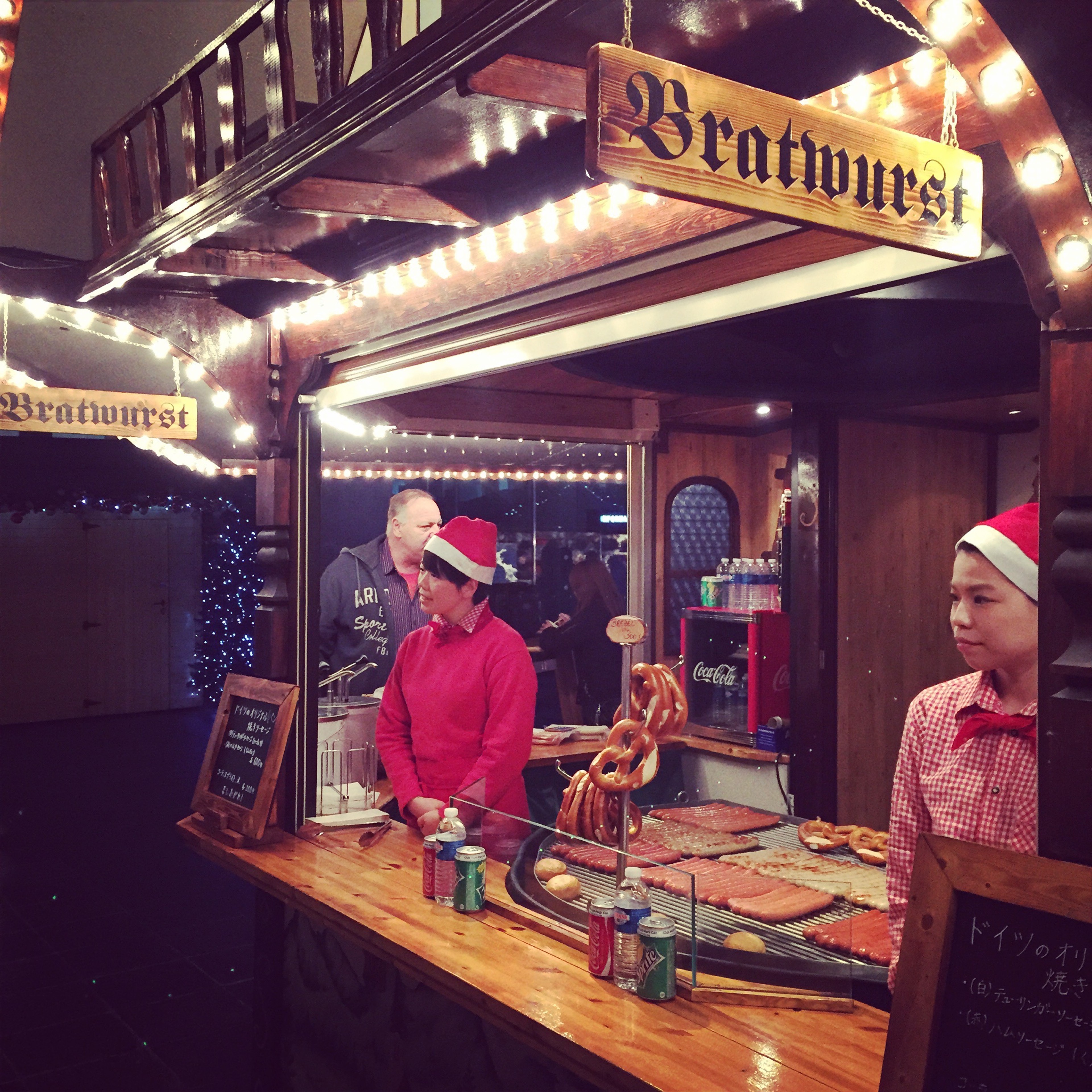 Two cooks work behind a brightly lit street food counter.