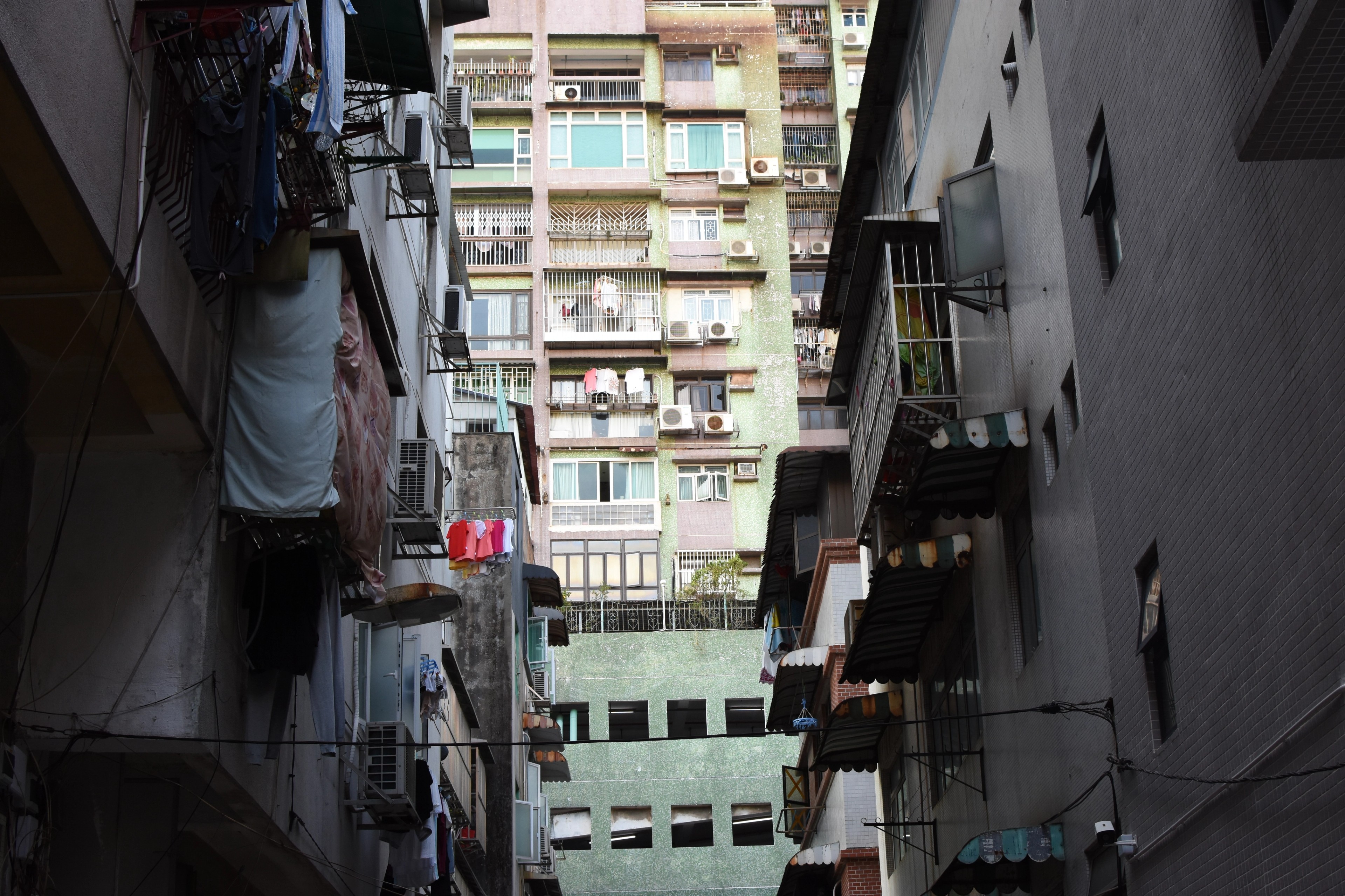 View upward through a narrow alley toward an old residential building.