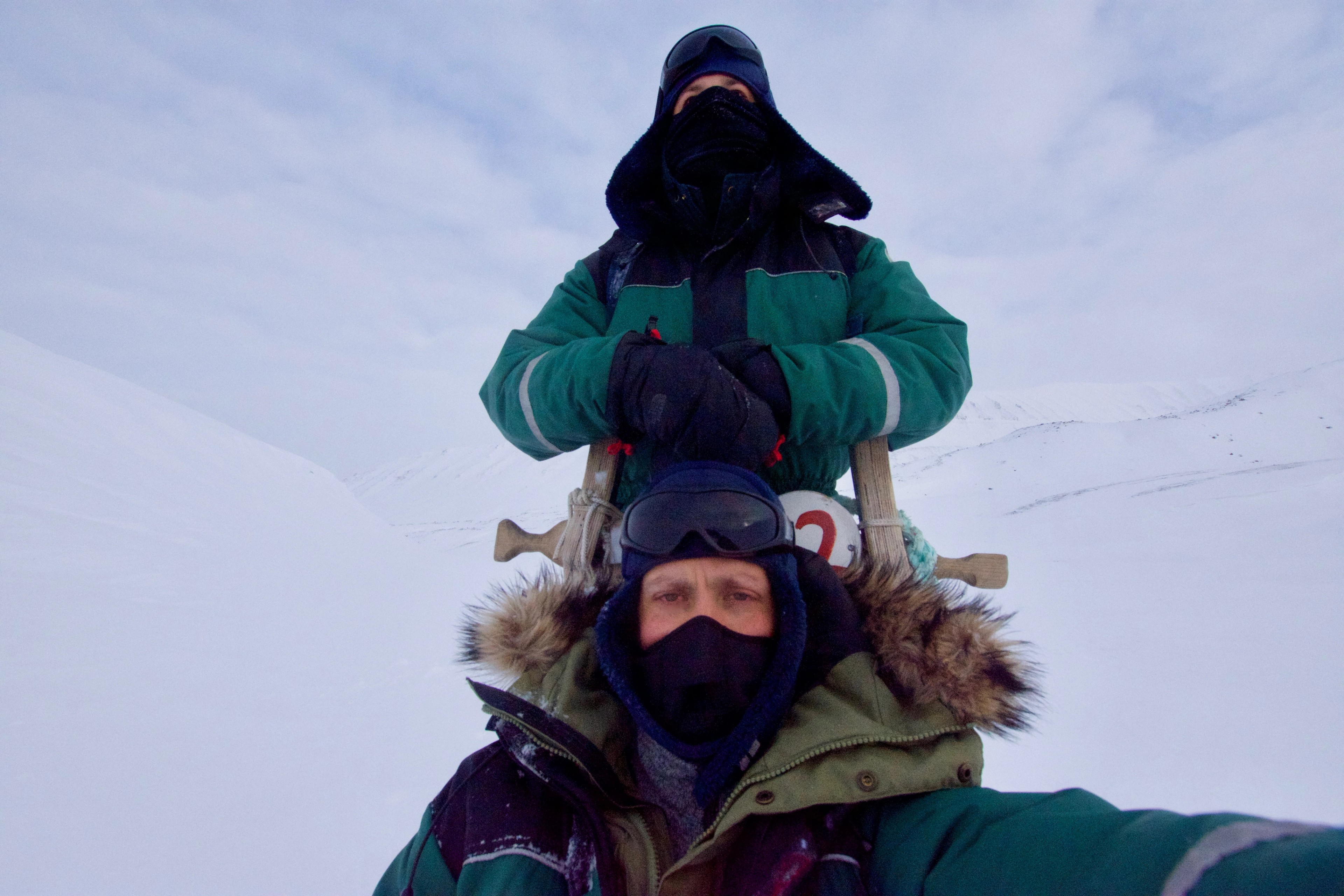 A person in a hood stands against the snow and ice.