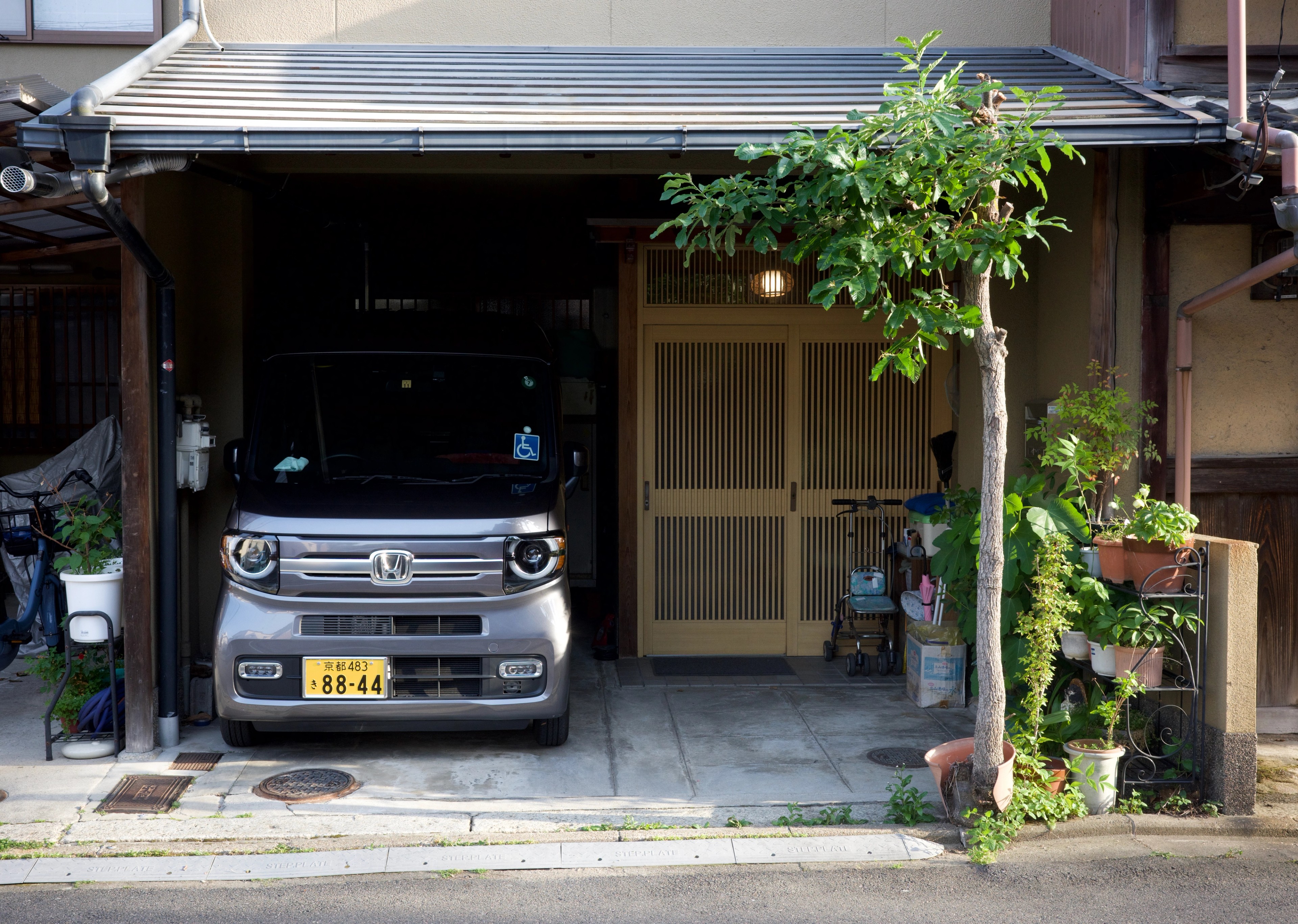 A compact van is parked before a home entrance.