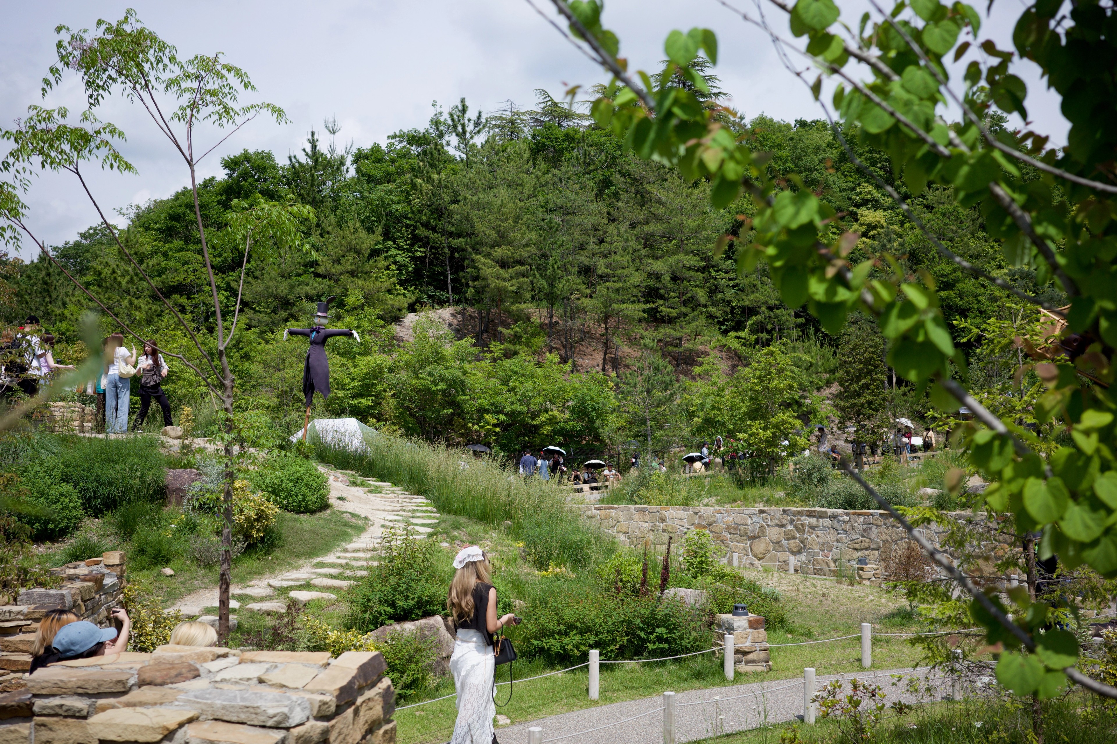 Visitors follow a path through a green hillside garden.