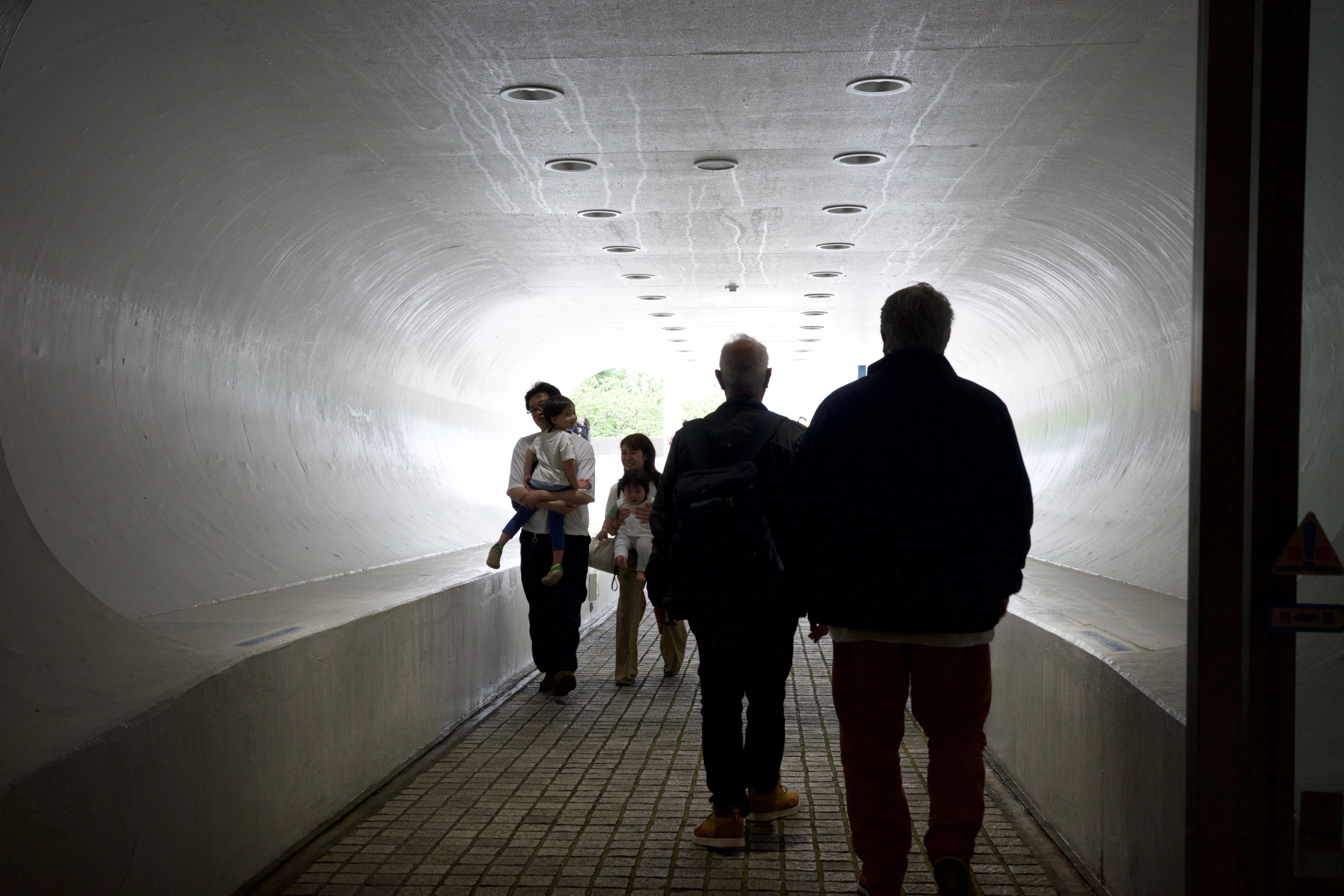 Visitors walk through a bright curved tunnel.