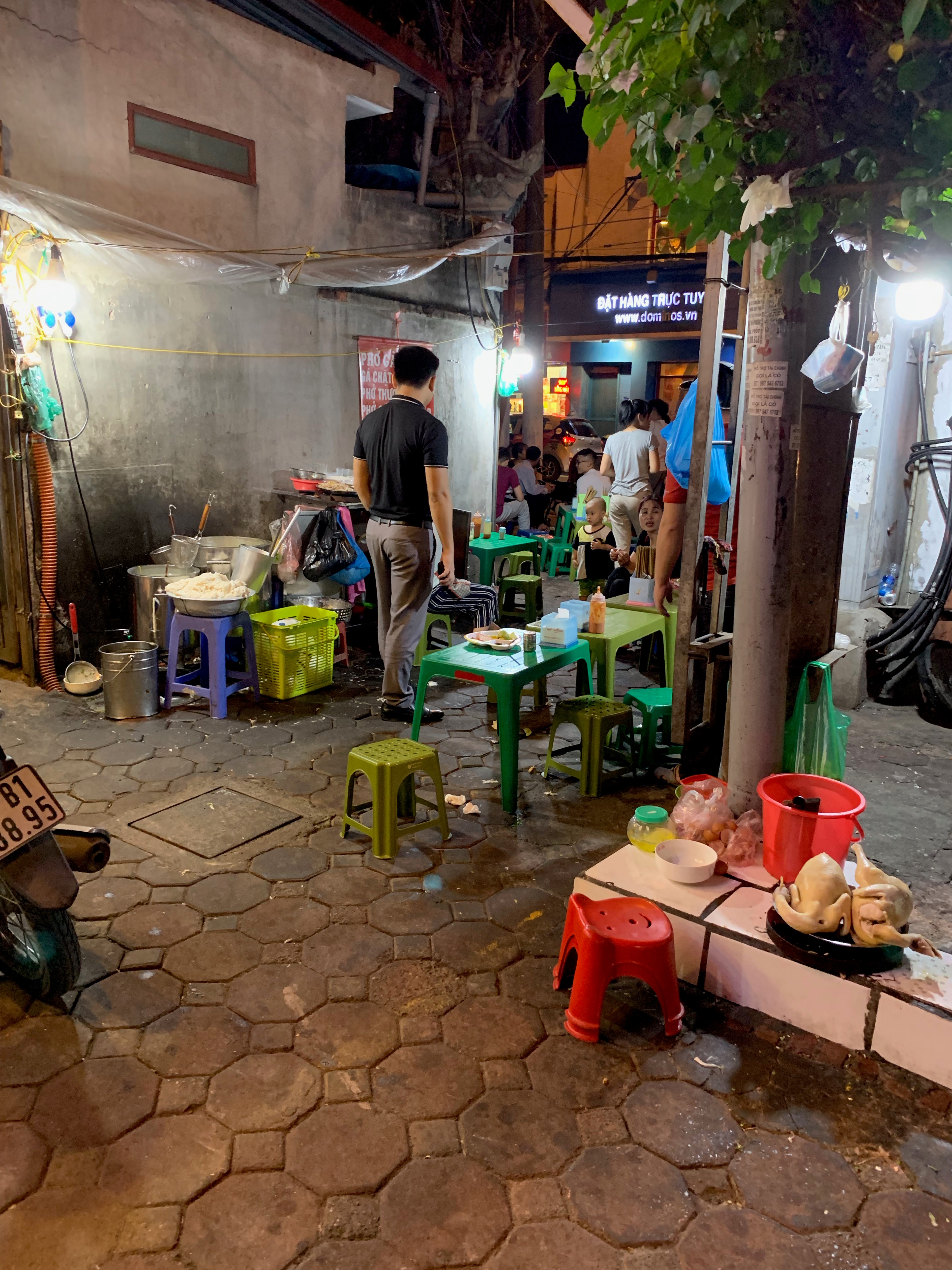 A small street-side food stall occupies a narrow paved lane.