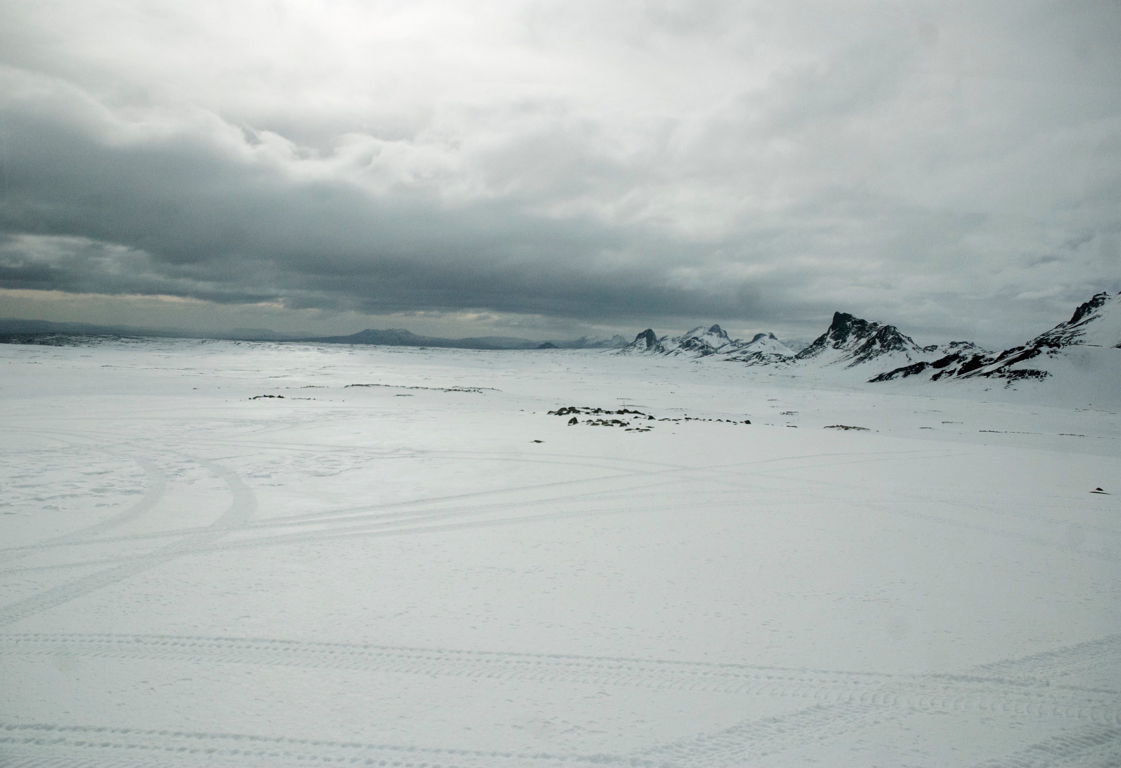 A wide snow-covered plain leads toward distant dark mountains.