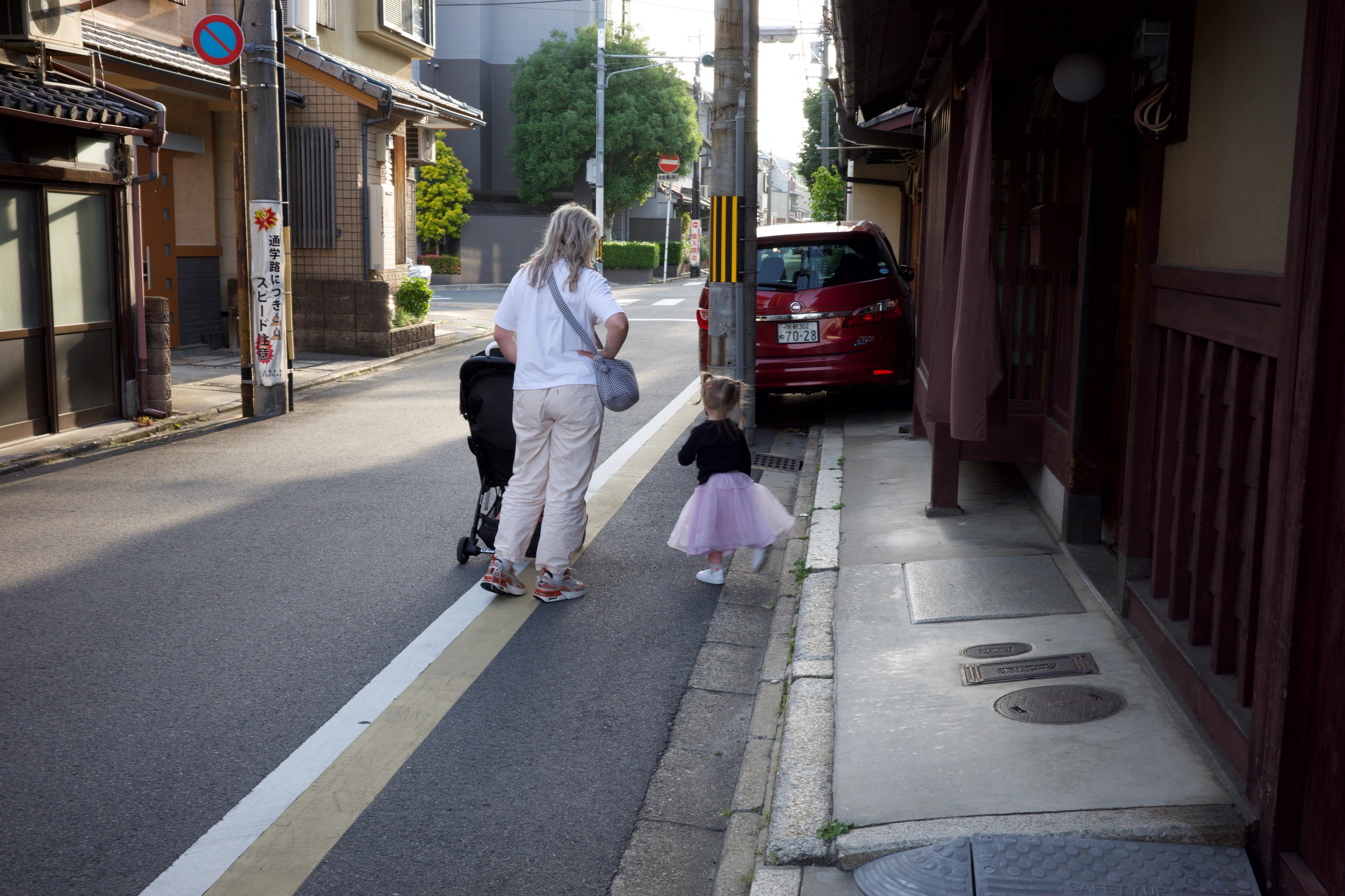 An adult walks with a child down a narrow street.
