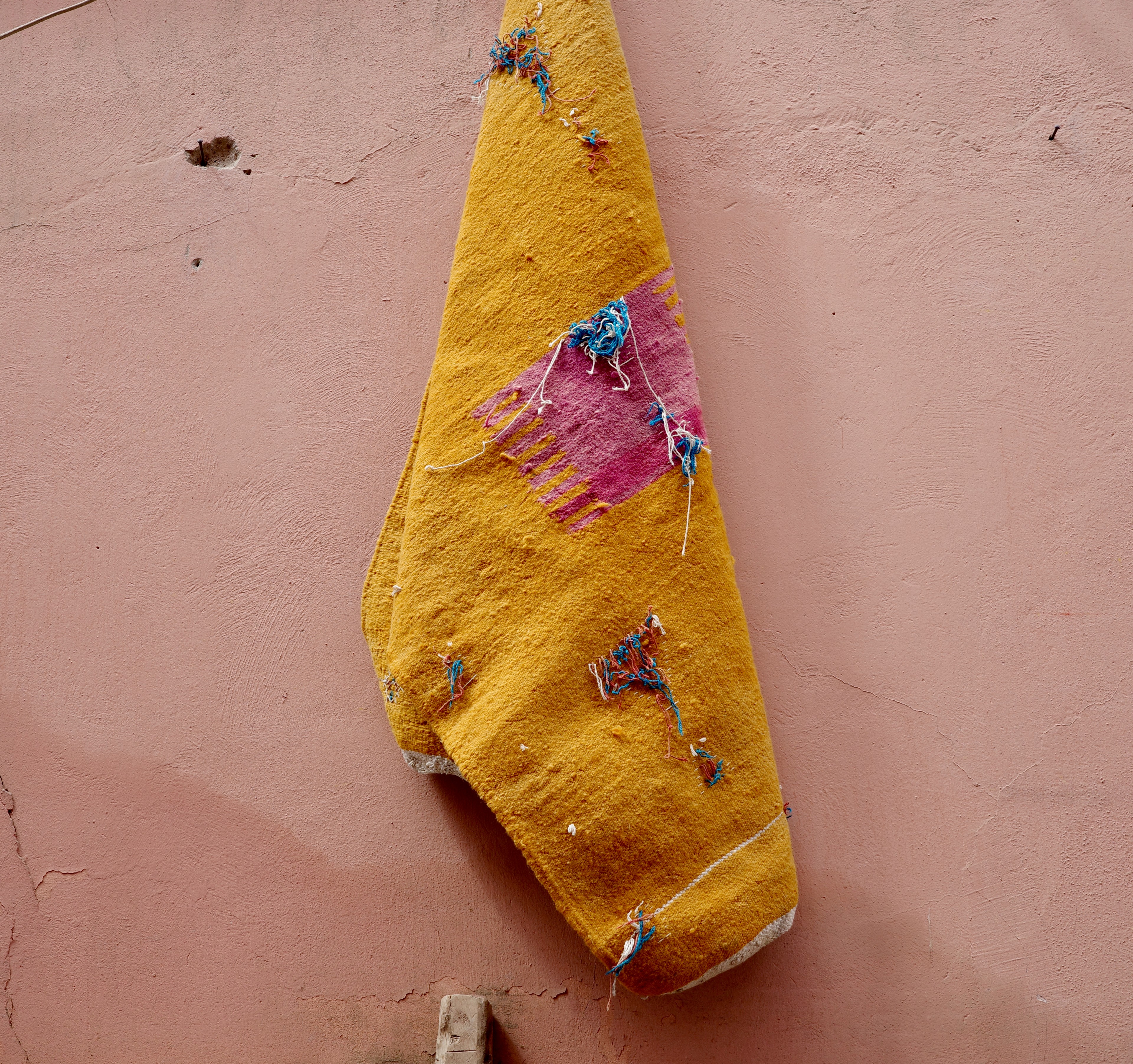 A small yellow object hangs from a pink wall.
