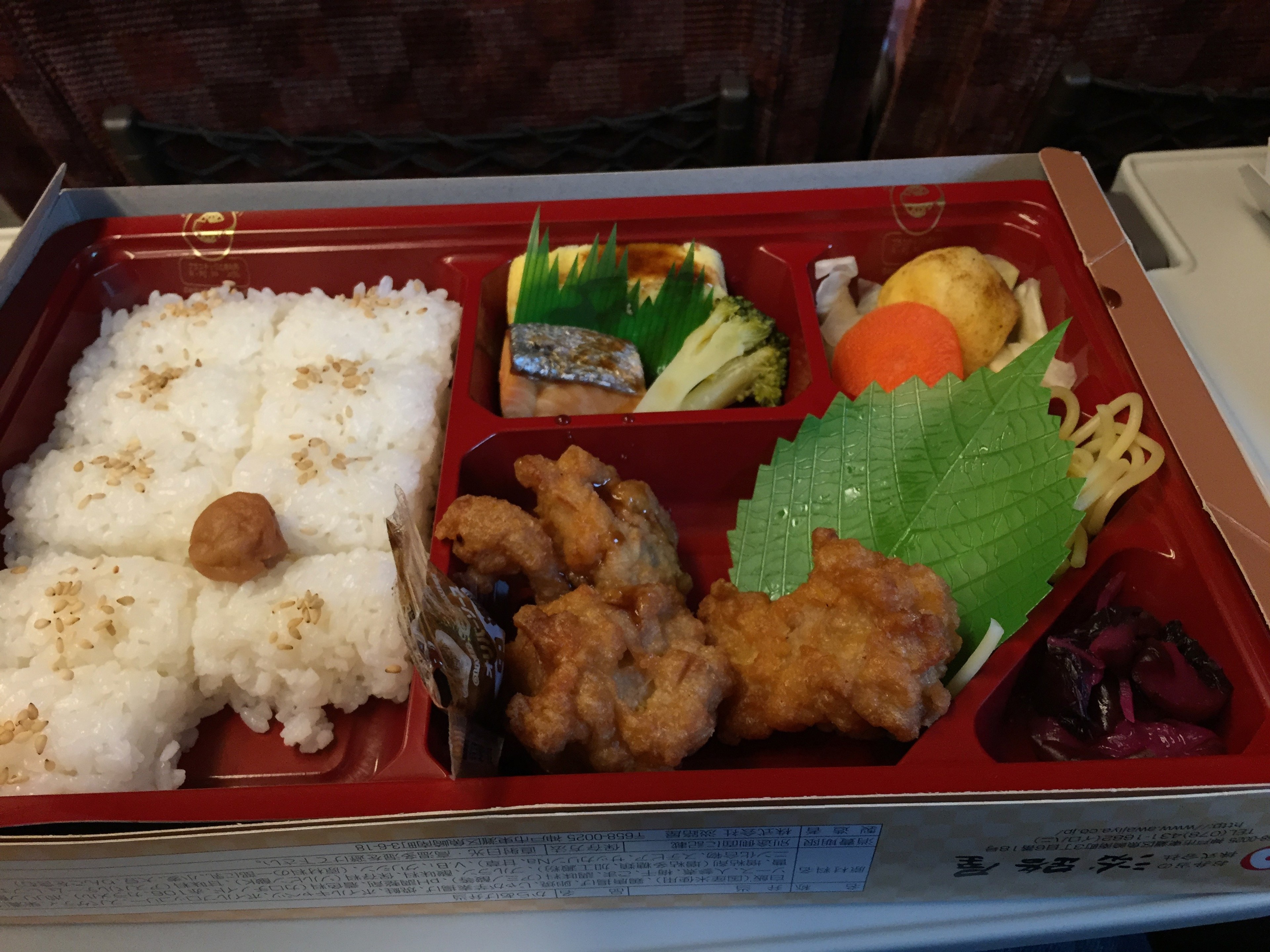 A bento box contains rice, fried chicken, and side dishes.