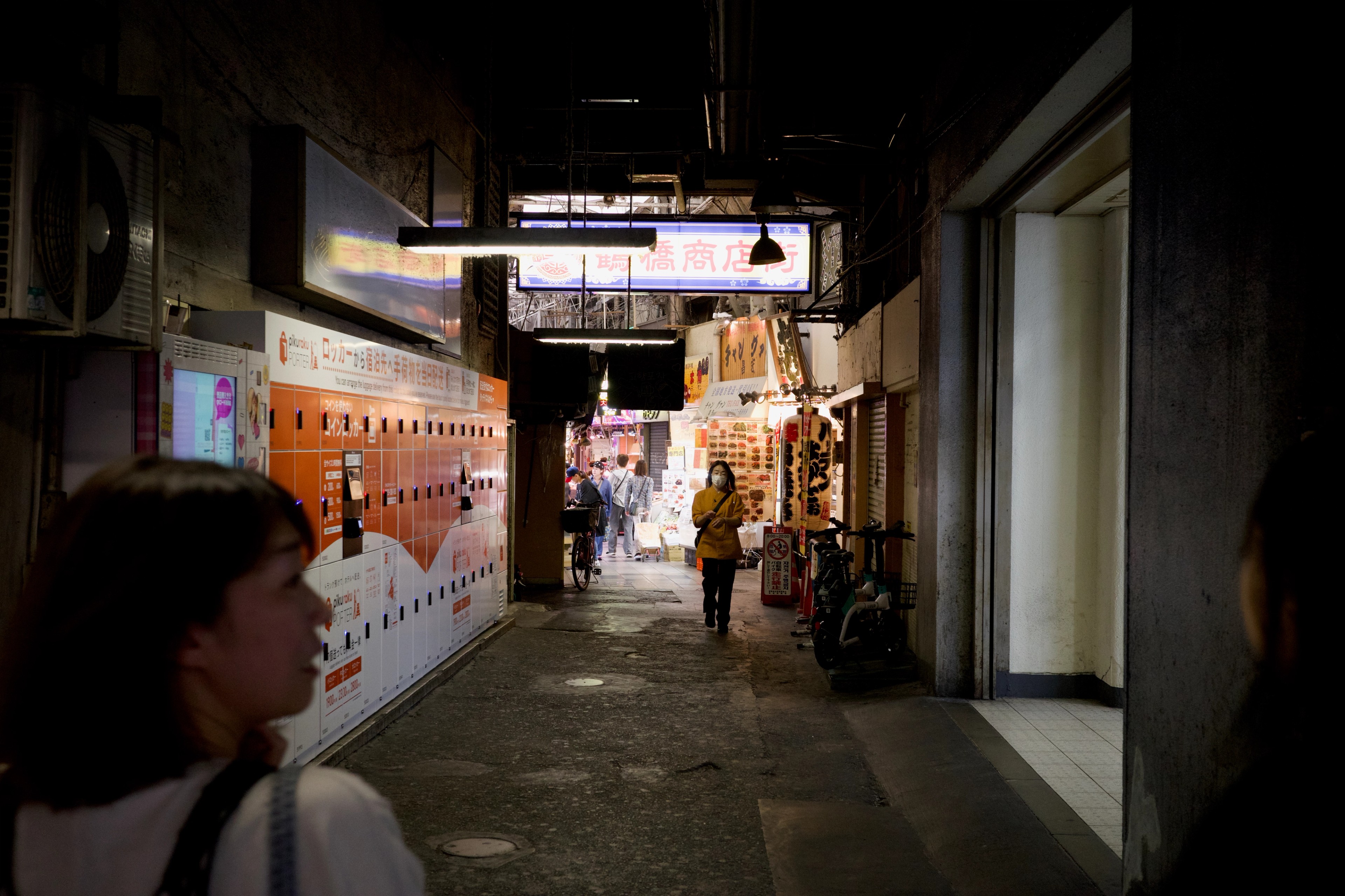 Pedestrians move through a brightly lit covered alley.