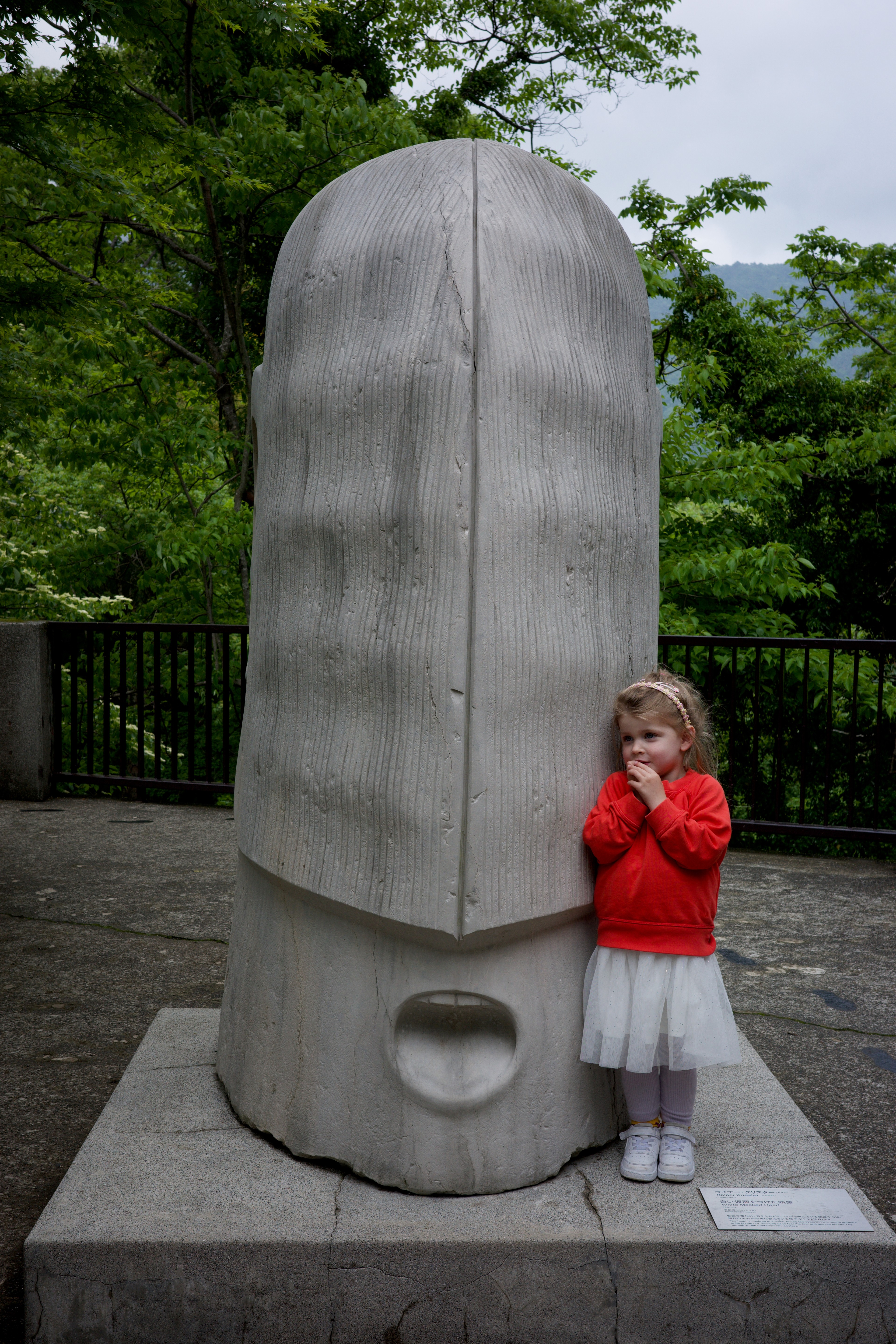A child stands beside a tall stone marker.