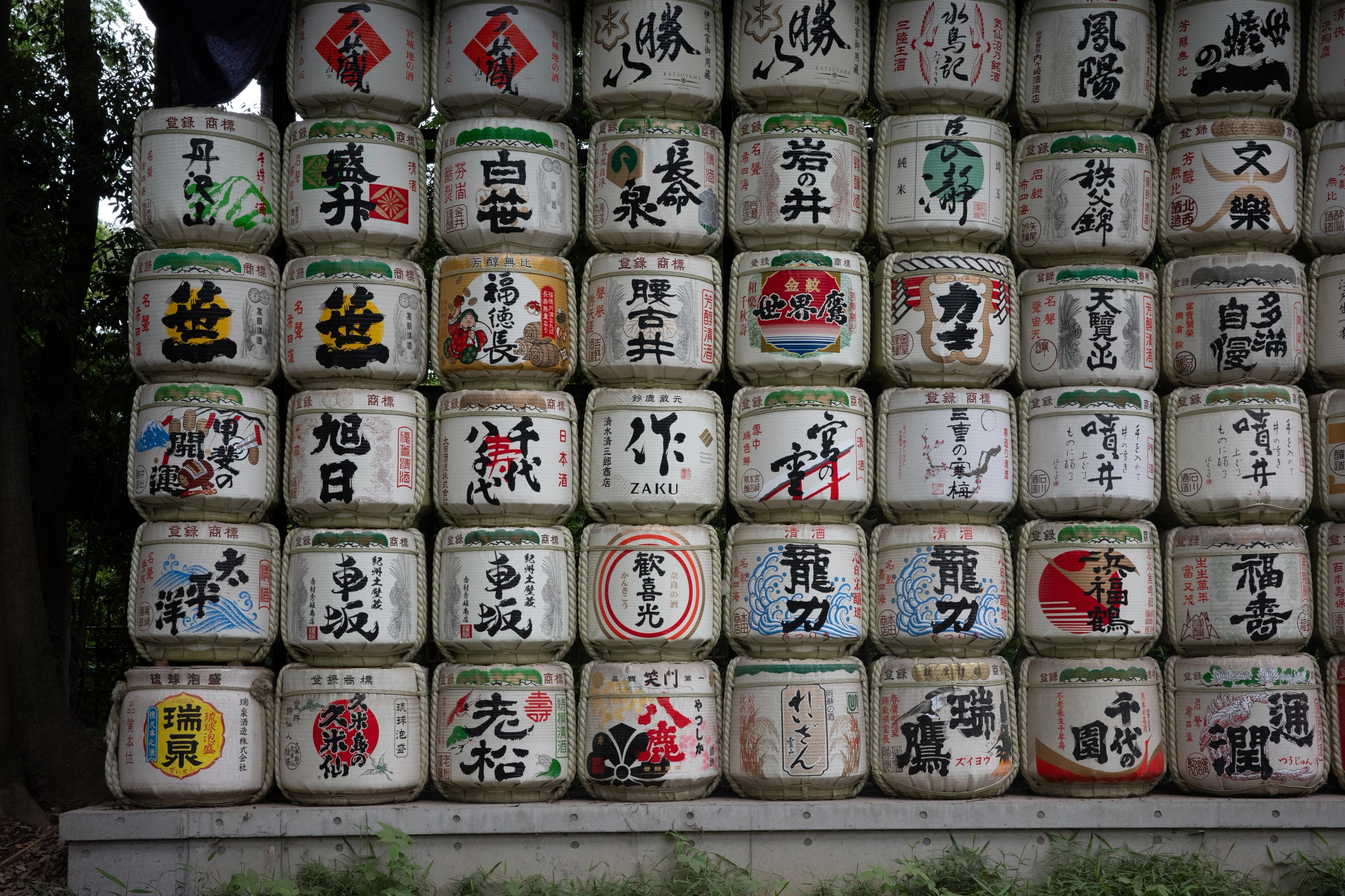 A wall of labeled sake barrels.