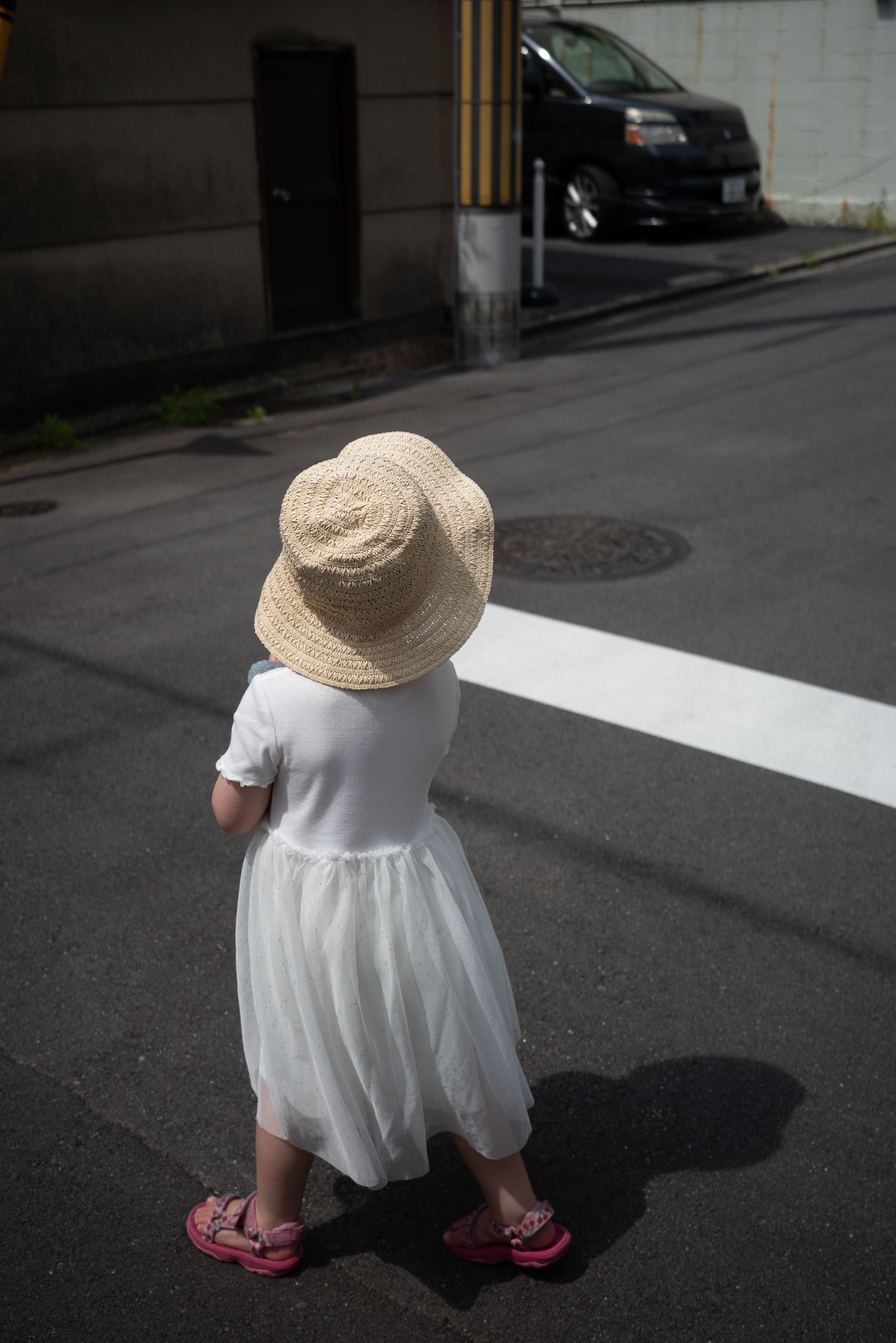A small child in a sun hat stands on a city street.