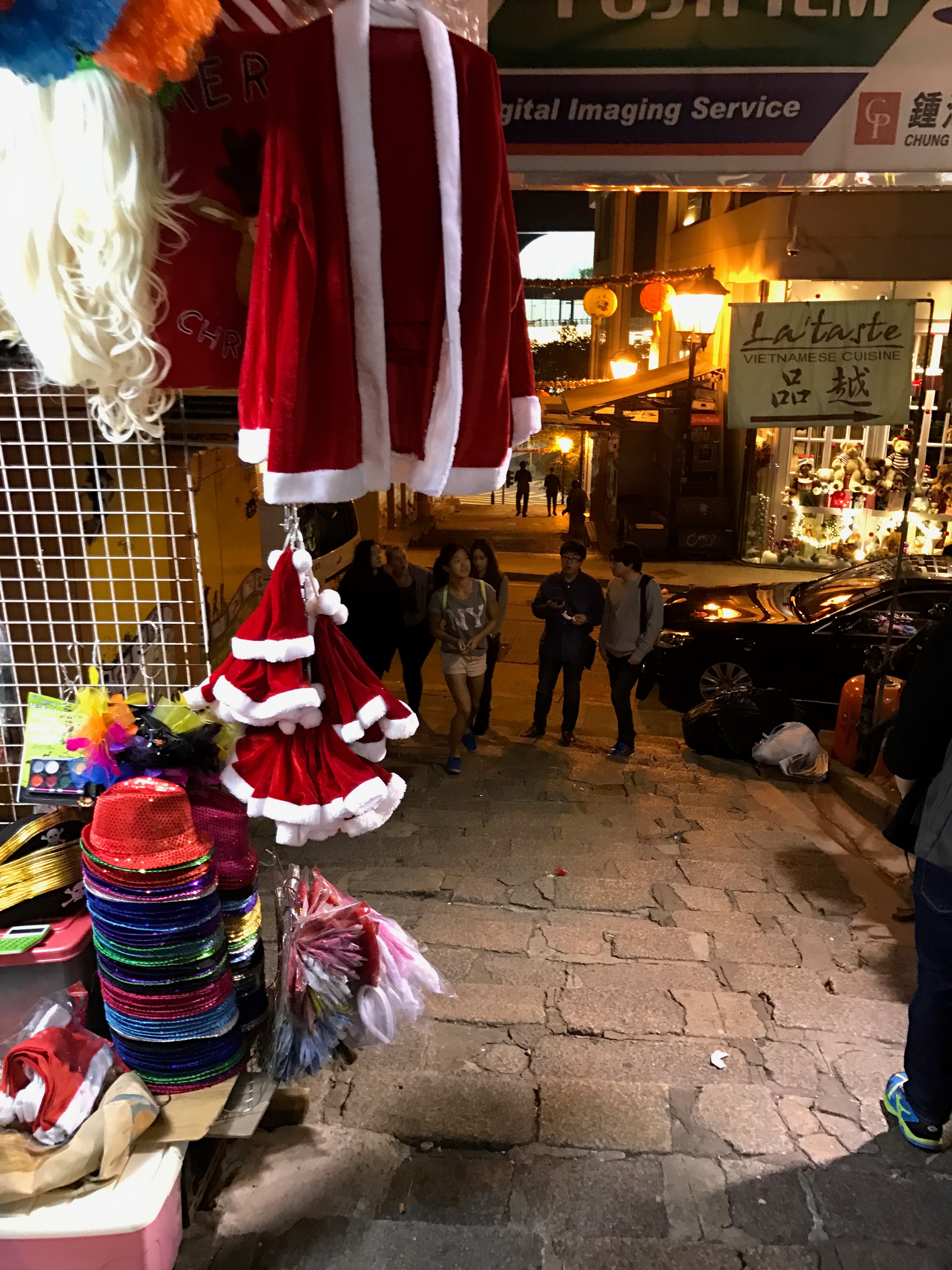 Red garments hang above a narrow clothing shop entrance.