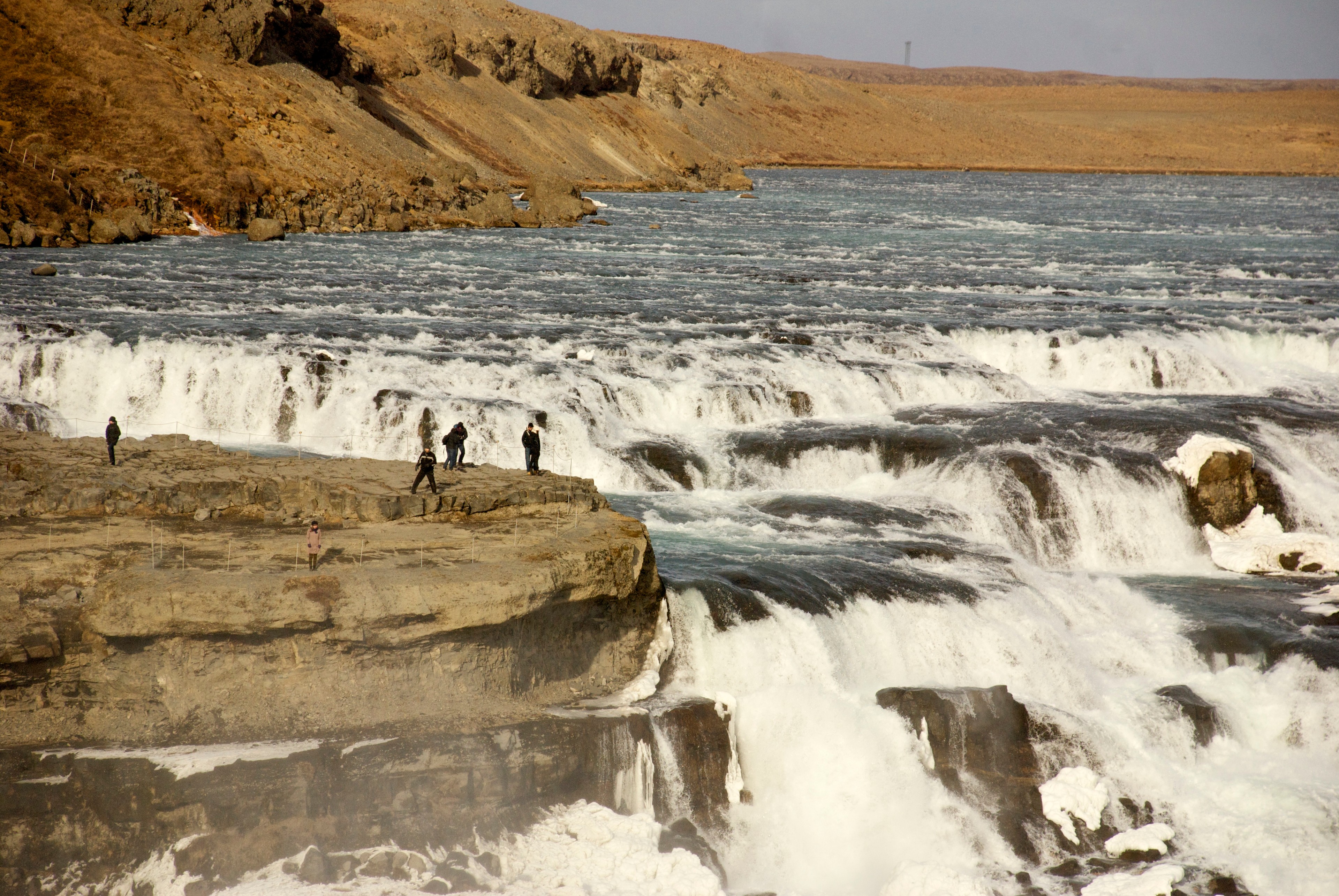 Water cascades over several rocky ledges into a river below.