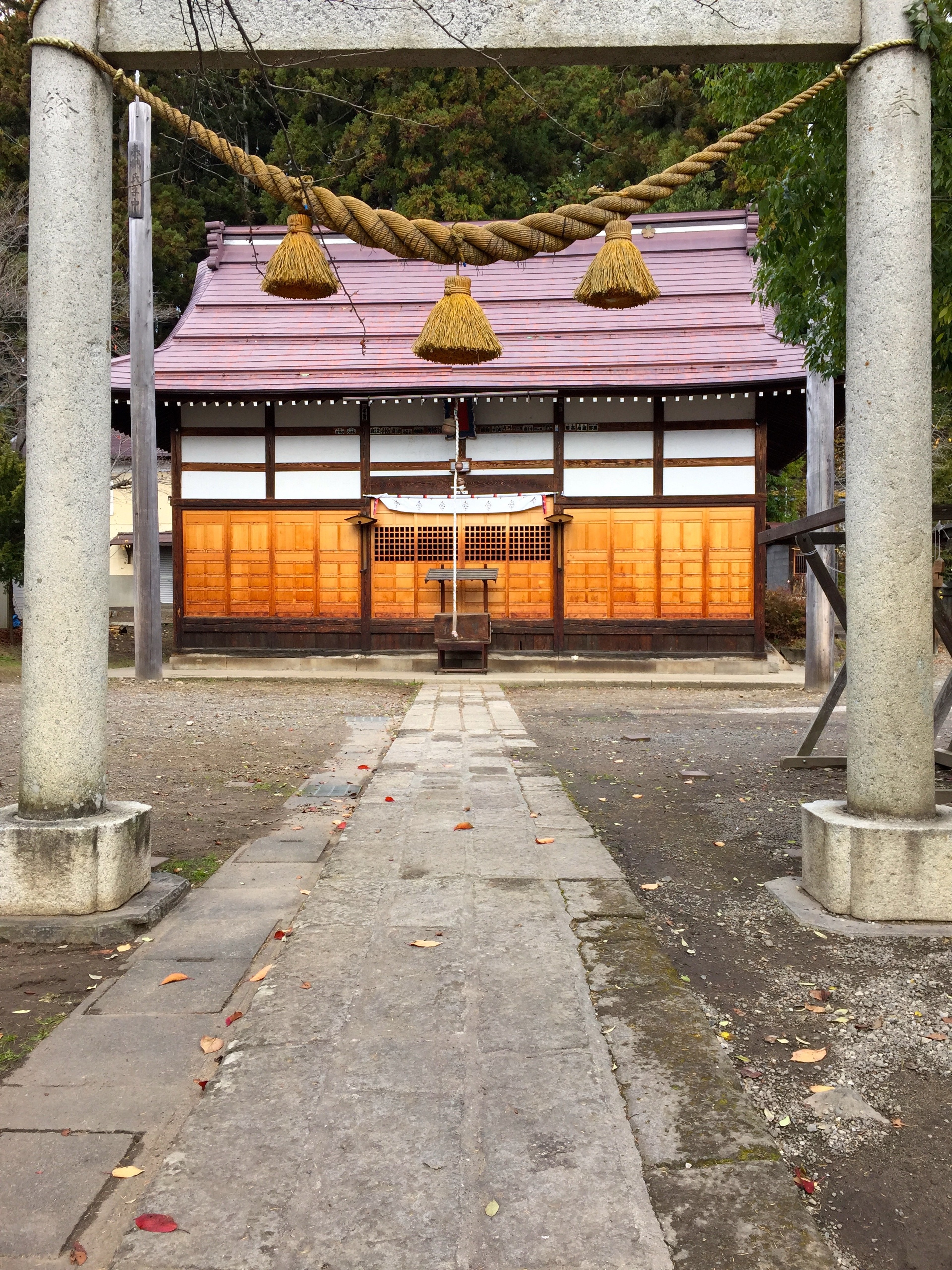 A small shrine stands at the end of a stone approach framed by a torii gate.