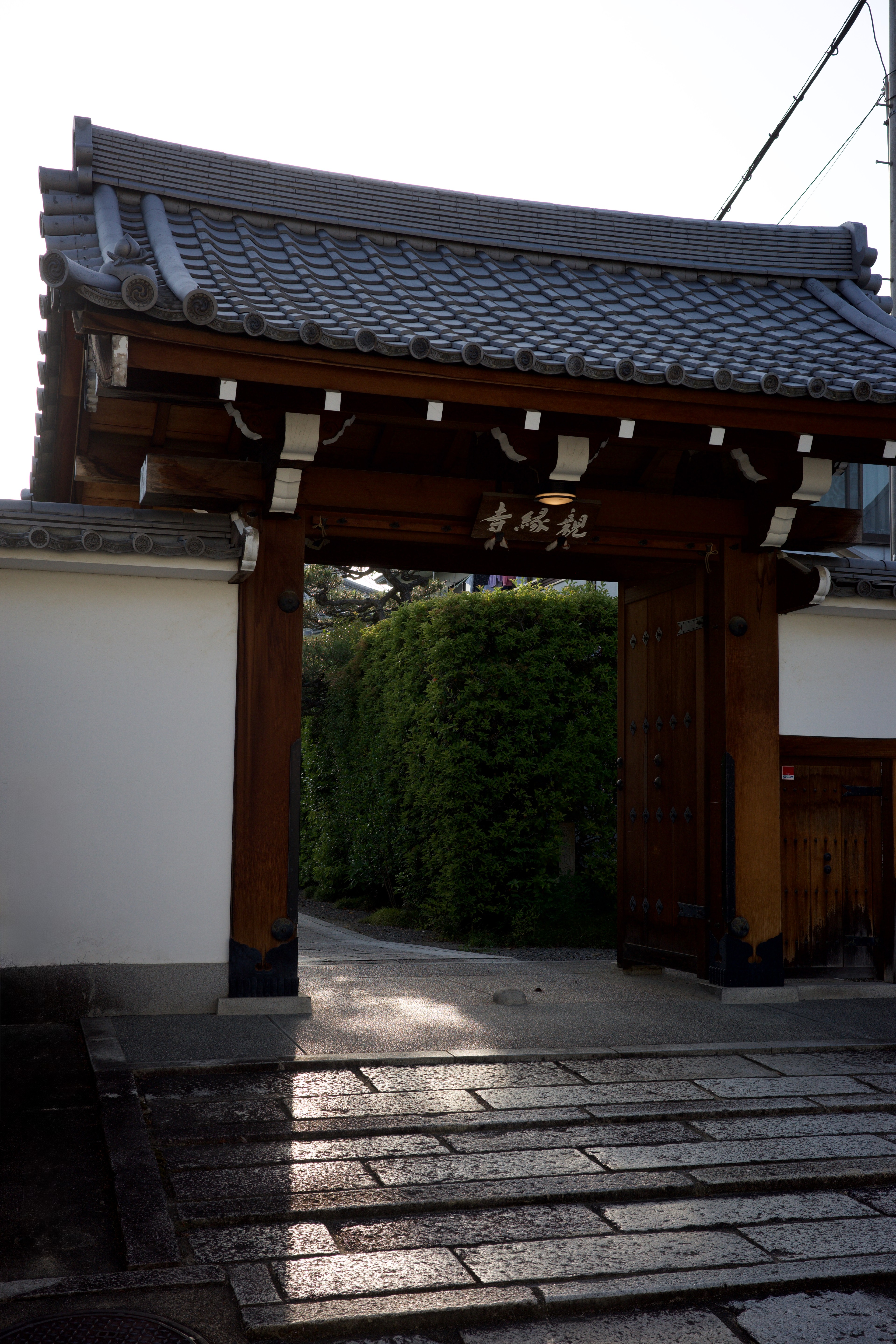 A wooden temple gate opens onto a stone path.
