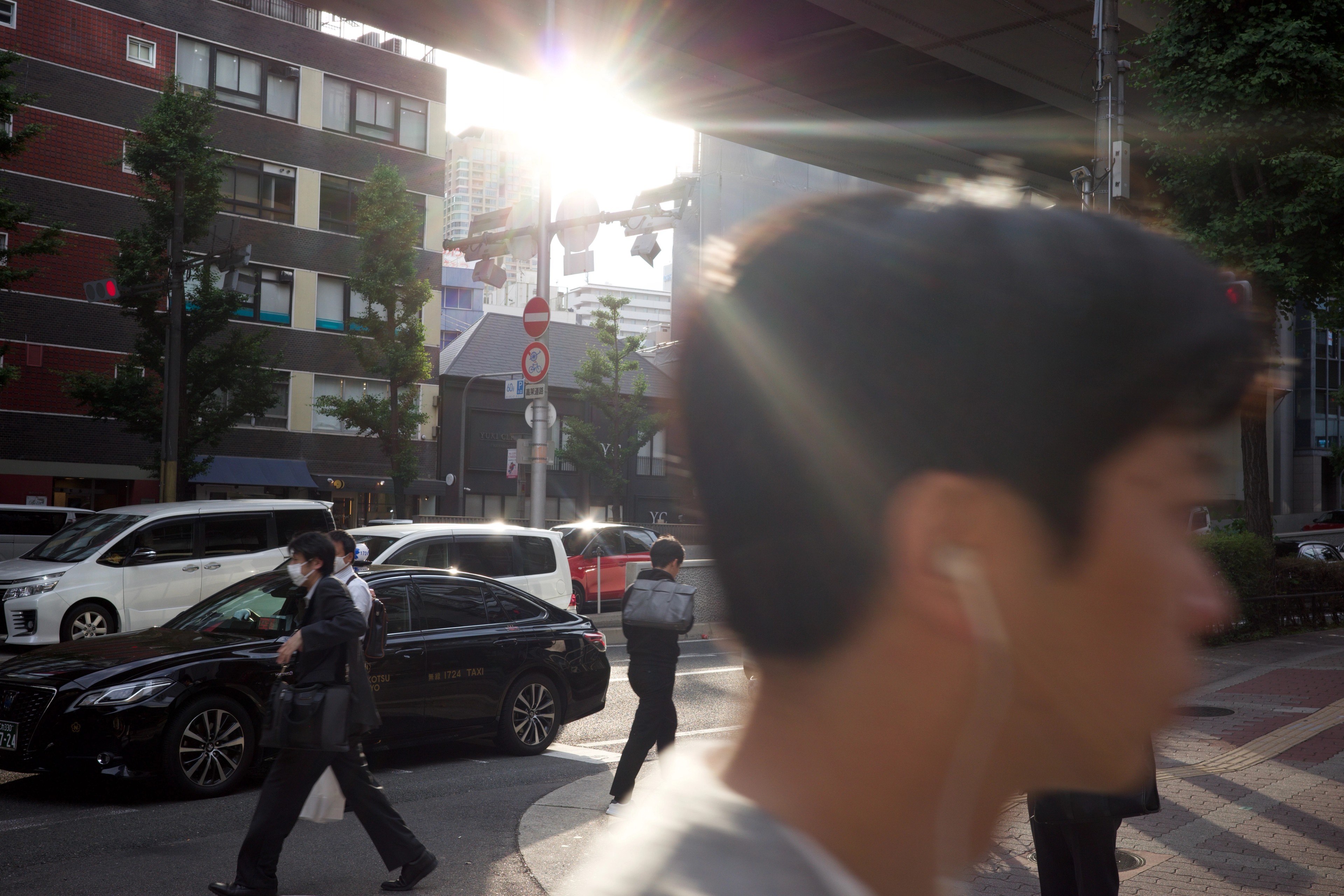 A pedestrian passes through a sunlit intersection.