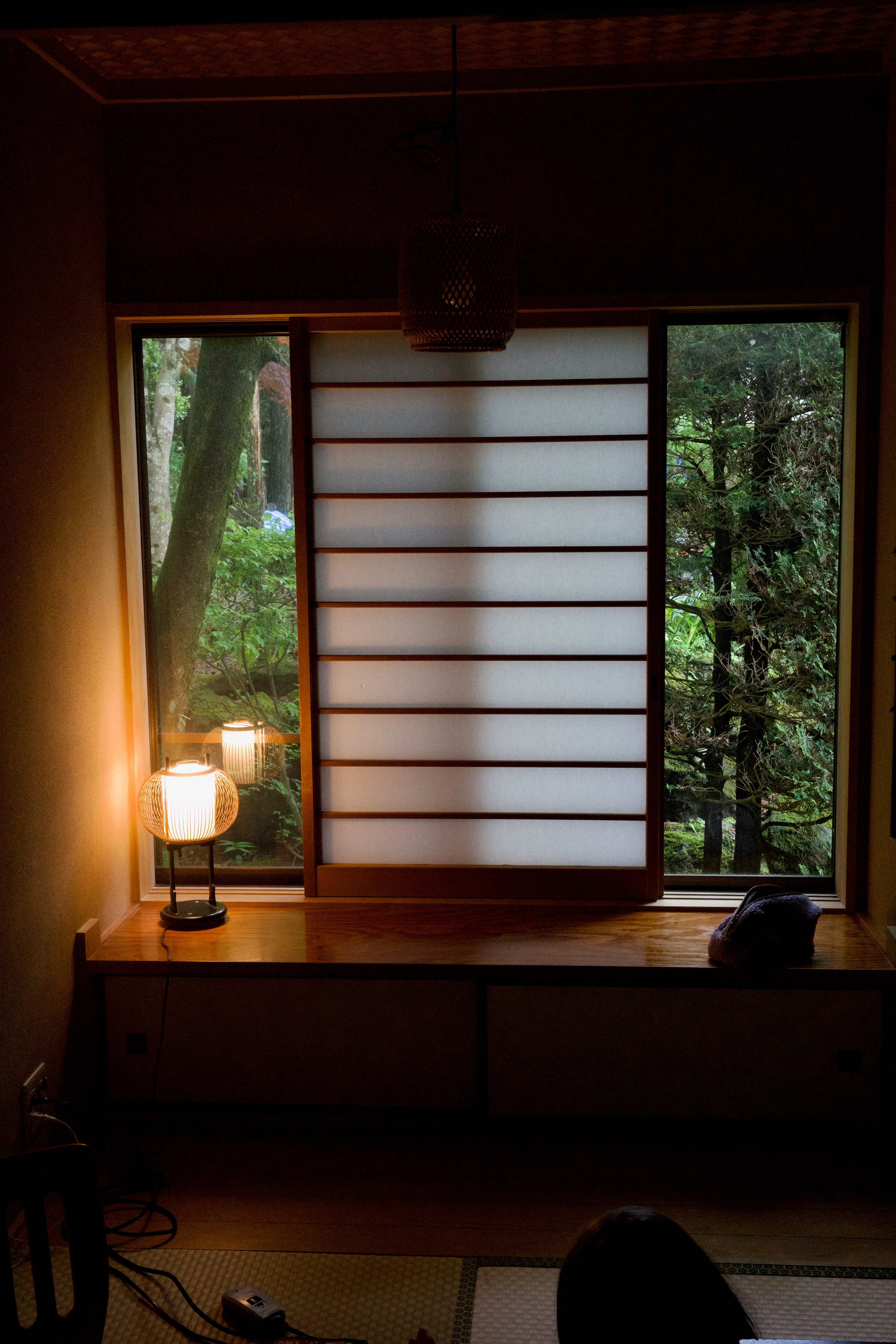 A lamp glows beside shoji screens in a dark room.