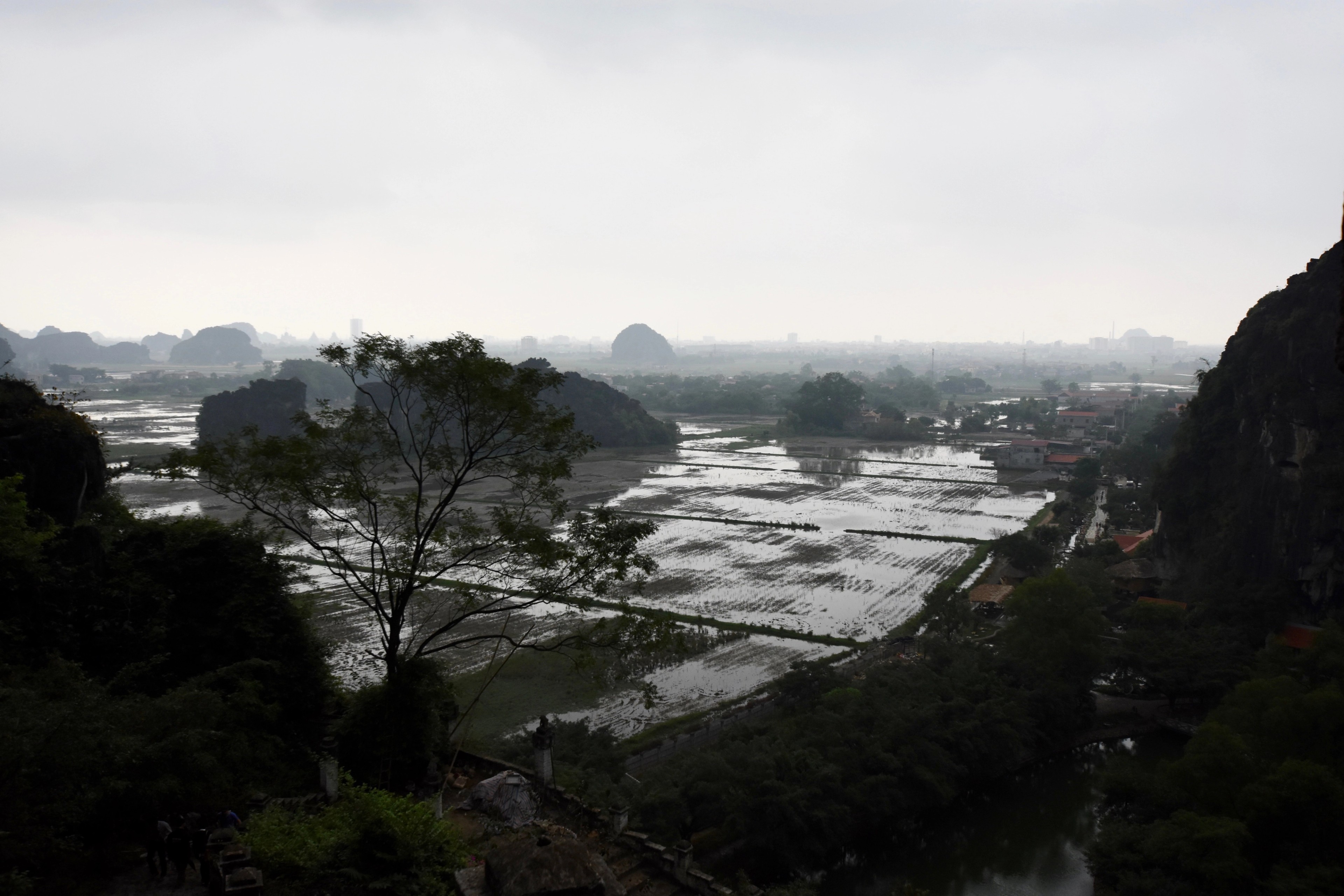 A hazy river plain spreads between distant limestone mountains.