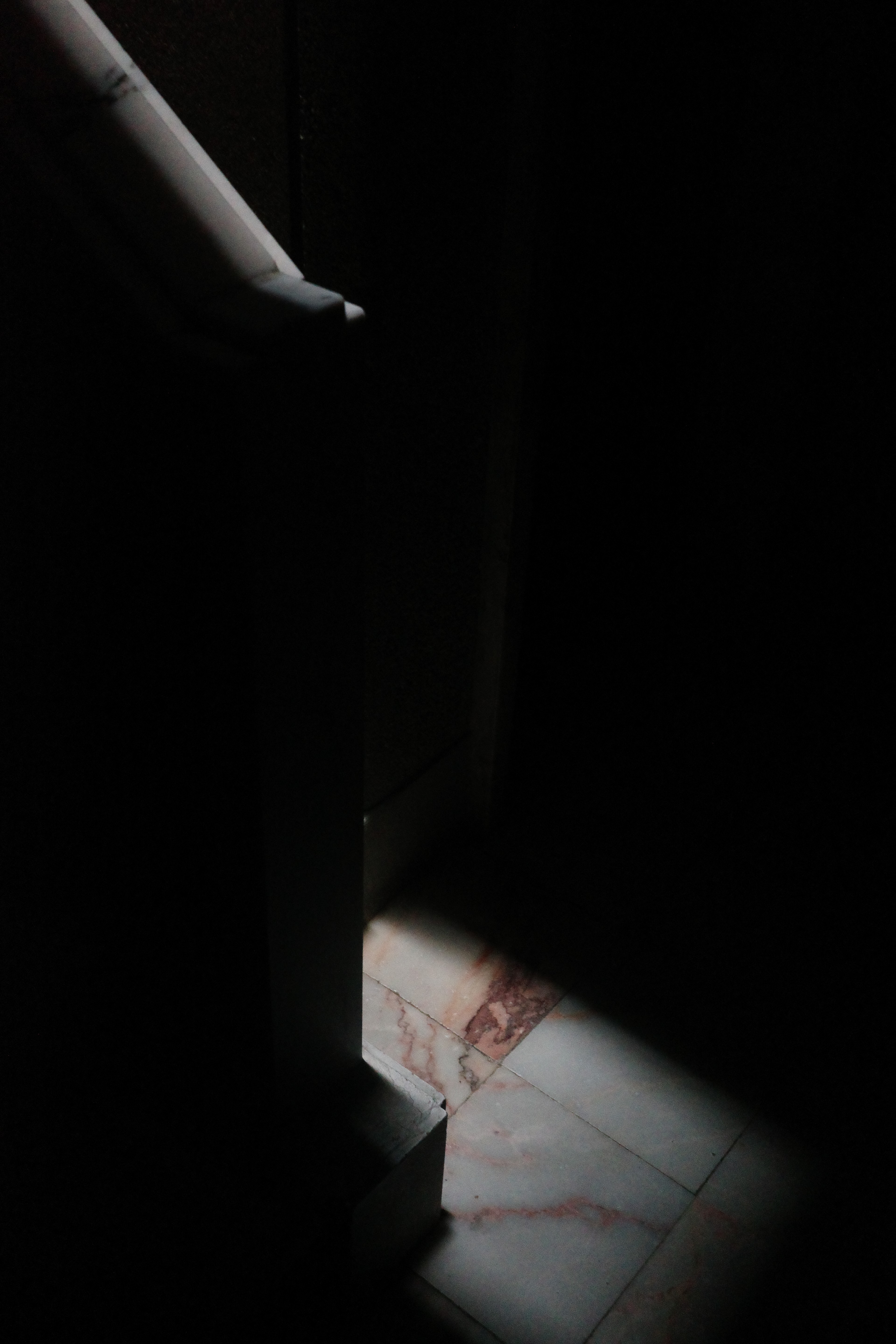 A sharp white angular form emerges from a nearly black gallery interior.