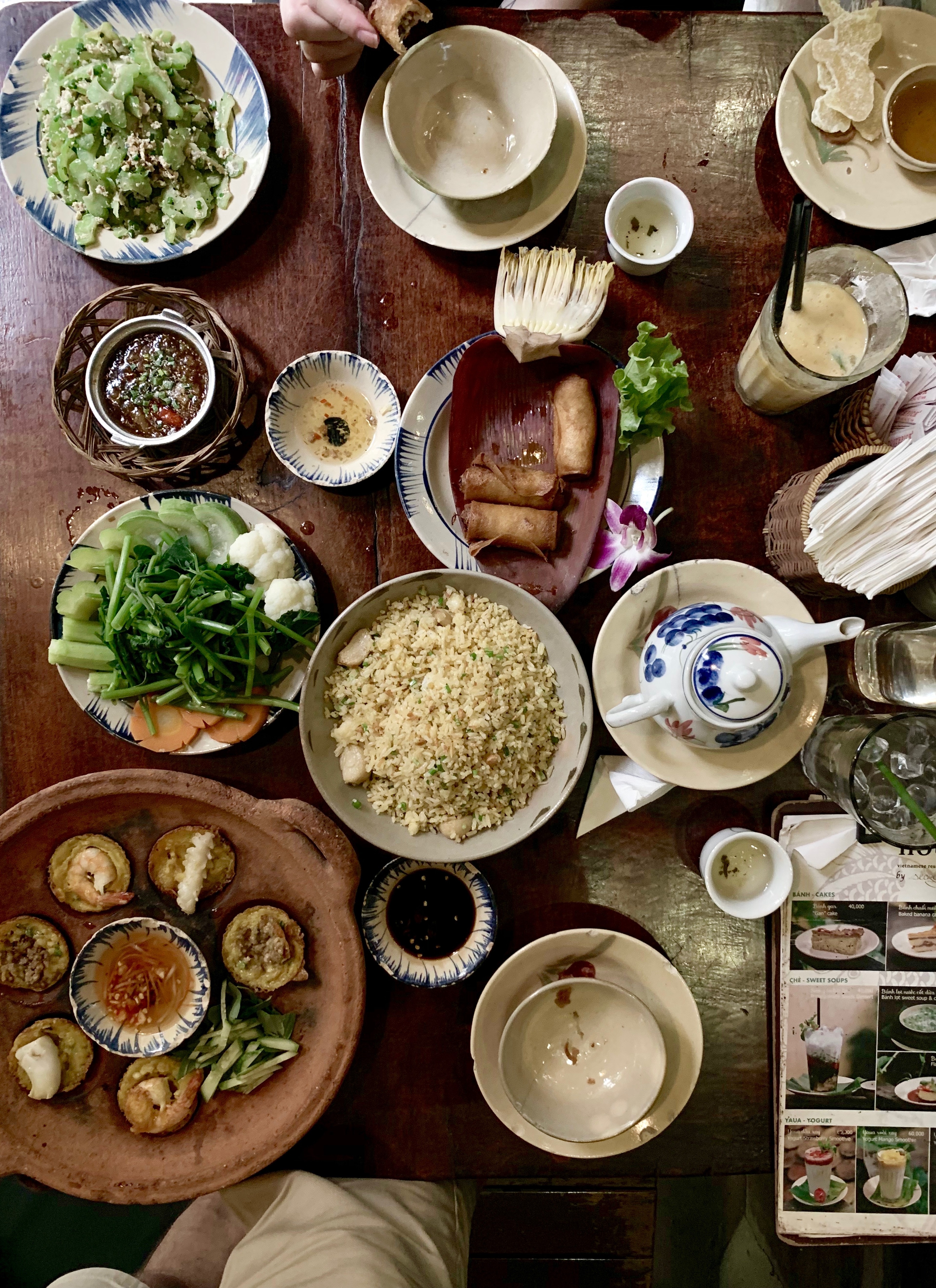 An overhead view of rice, vegetables, sauces, and several shared dishes.