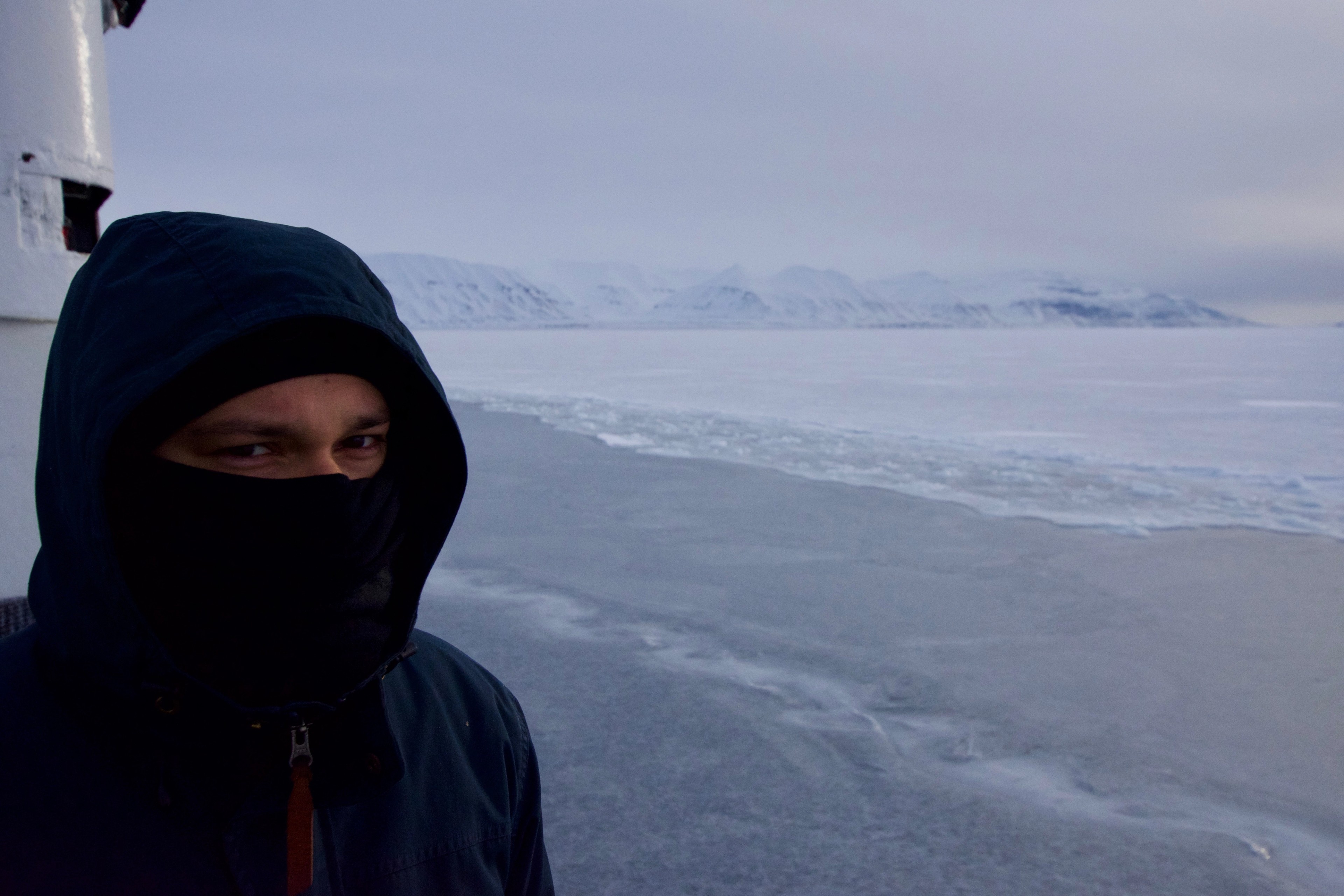 A bundled person stands beside a frozen coastline.