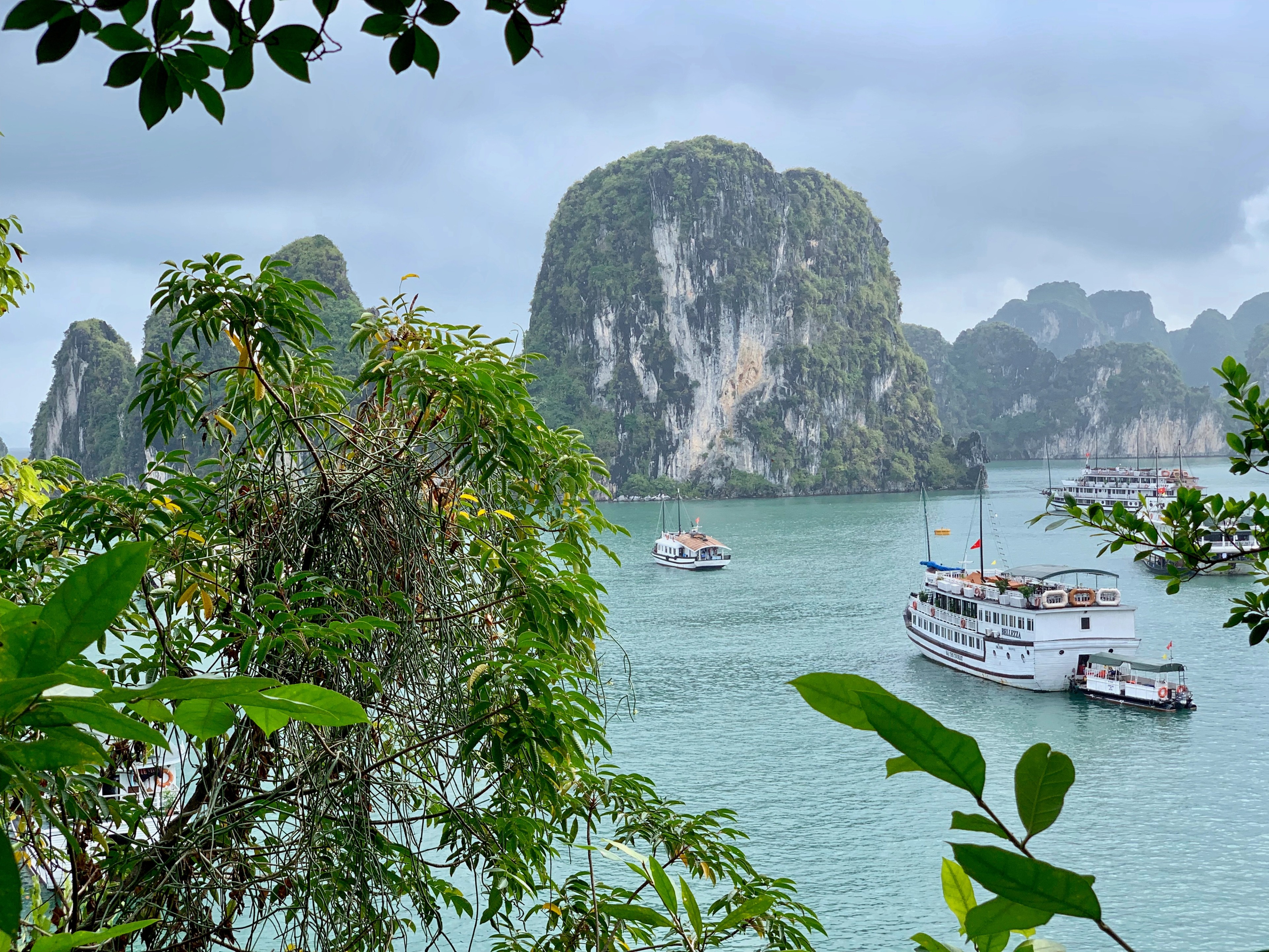 Several boats float in a bay framed by green limestone islands.
