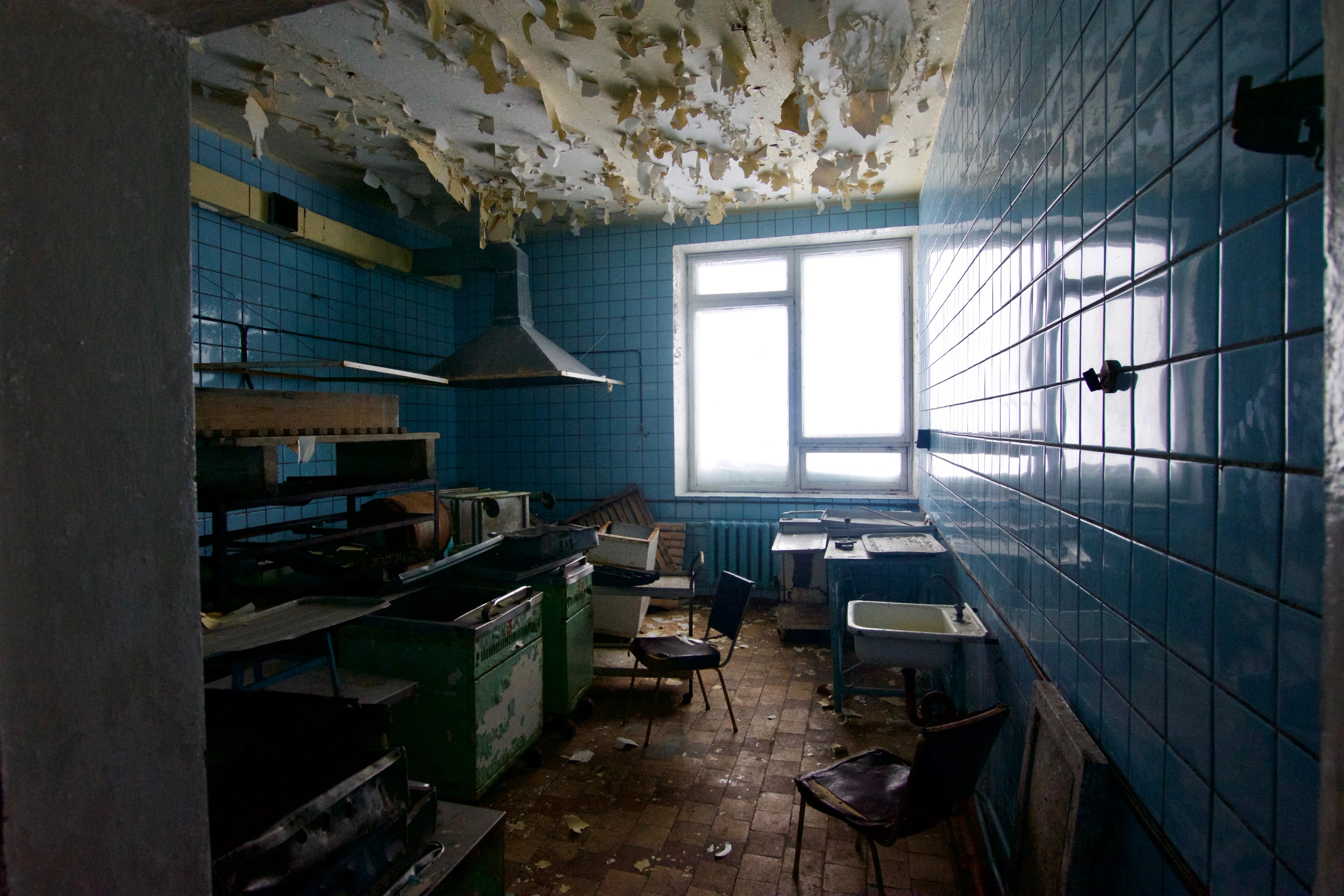 A small tiled room contains old fixtures and peeling walls.