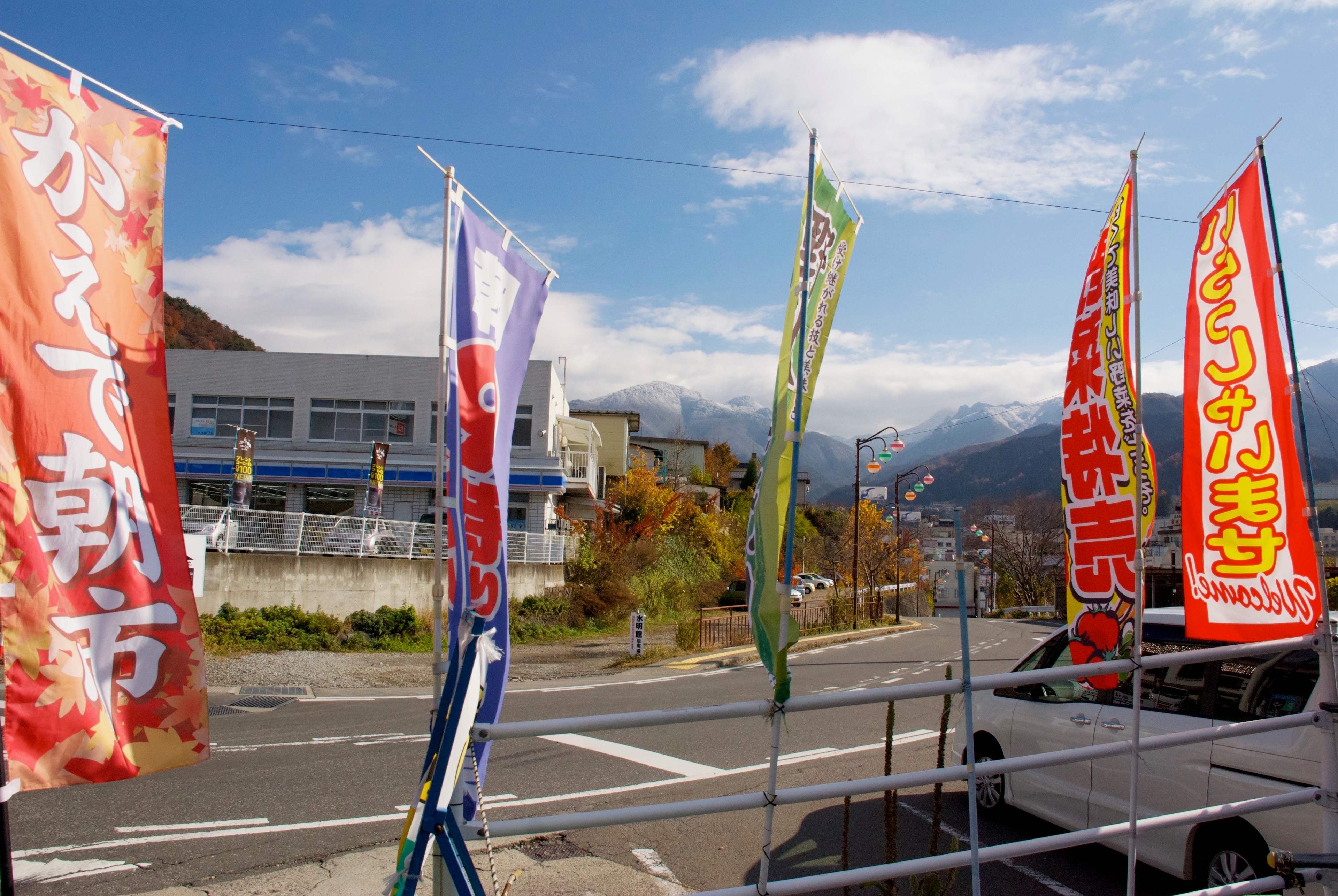 Colorful flags stand outside a roadside shop beneath a blue sky.
