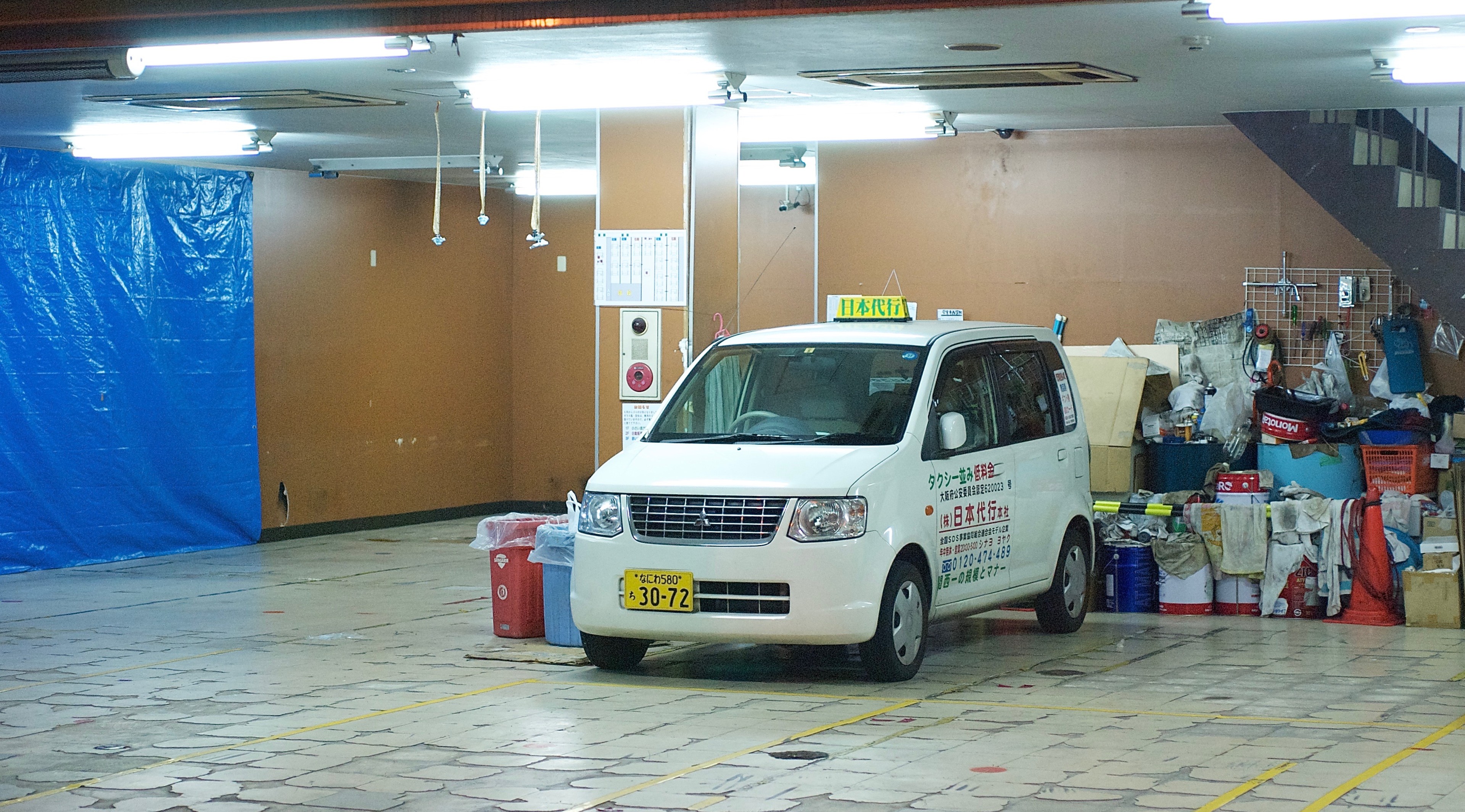 A white van is parked in a brightly lit underground service area.