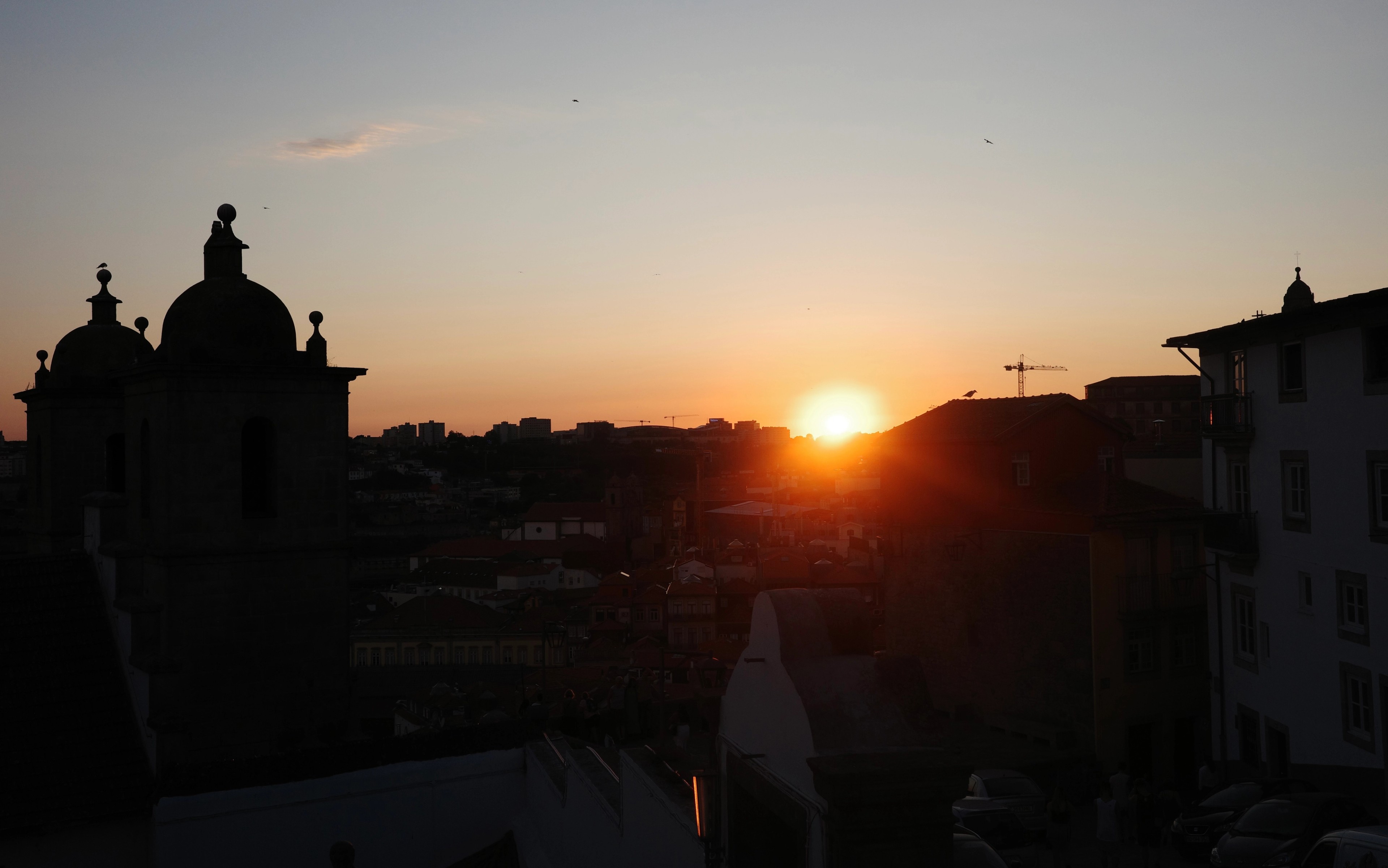 The sun sets behind the dark rooftops and church towers of Porto.