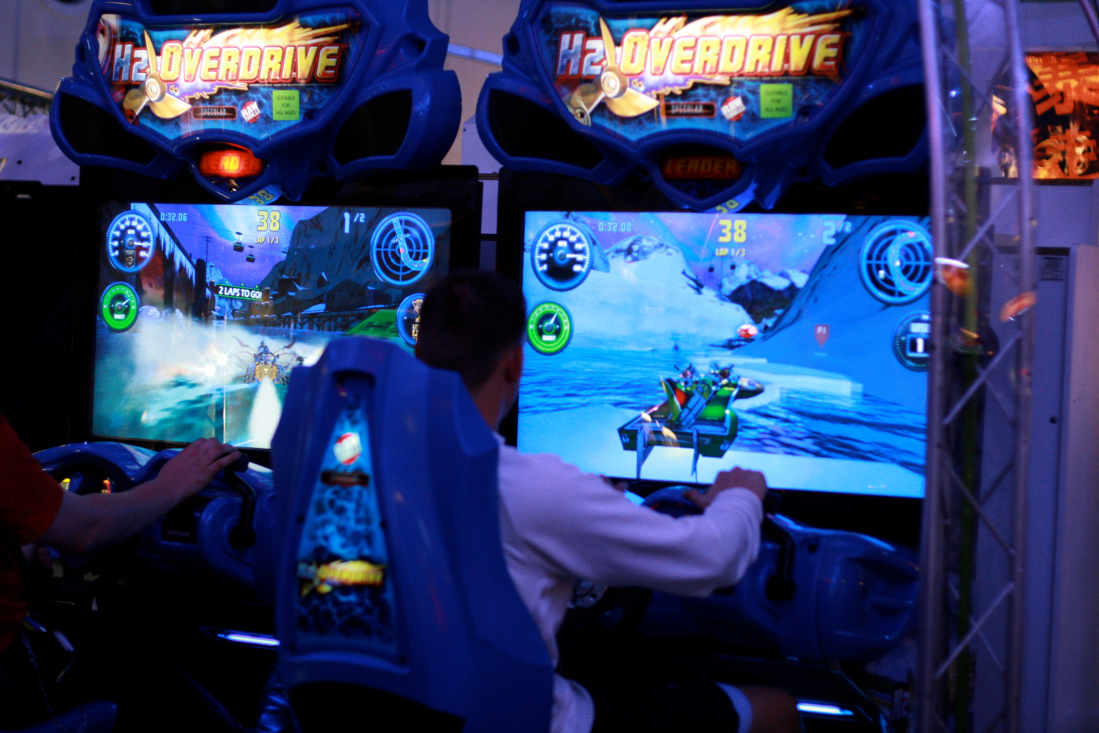 A child plays an arcade racing game in a dimly lit amusement arcade.