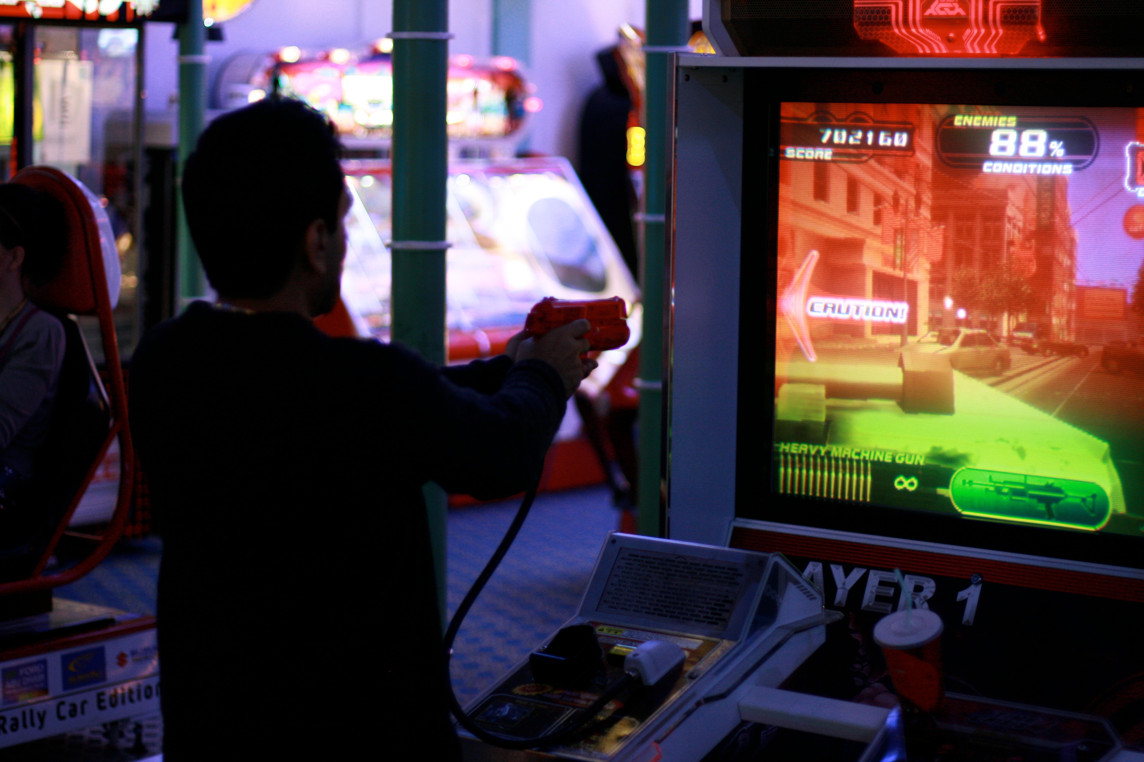 A person plays an arcade game in a neon-lit room.