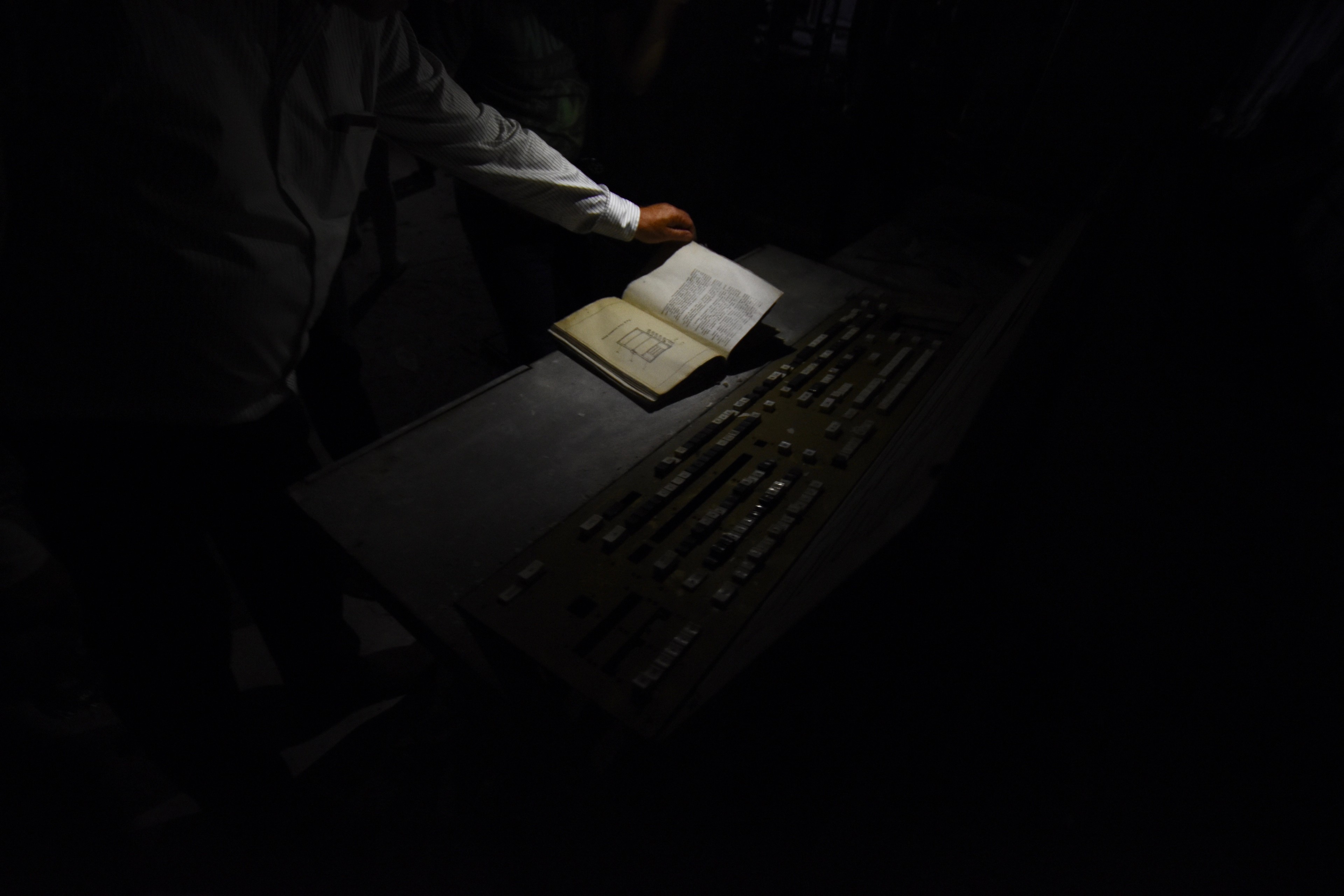 A hand turns through a book on a dark control console.