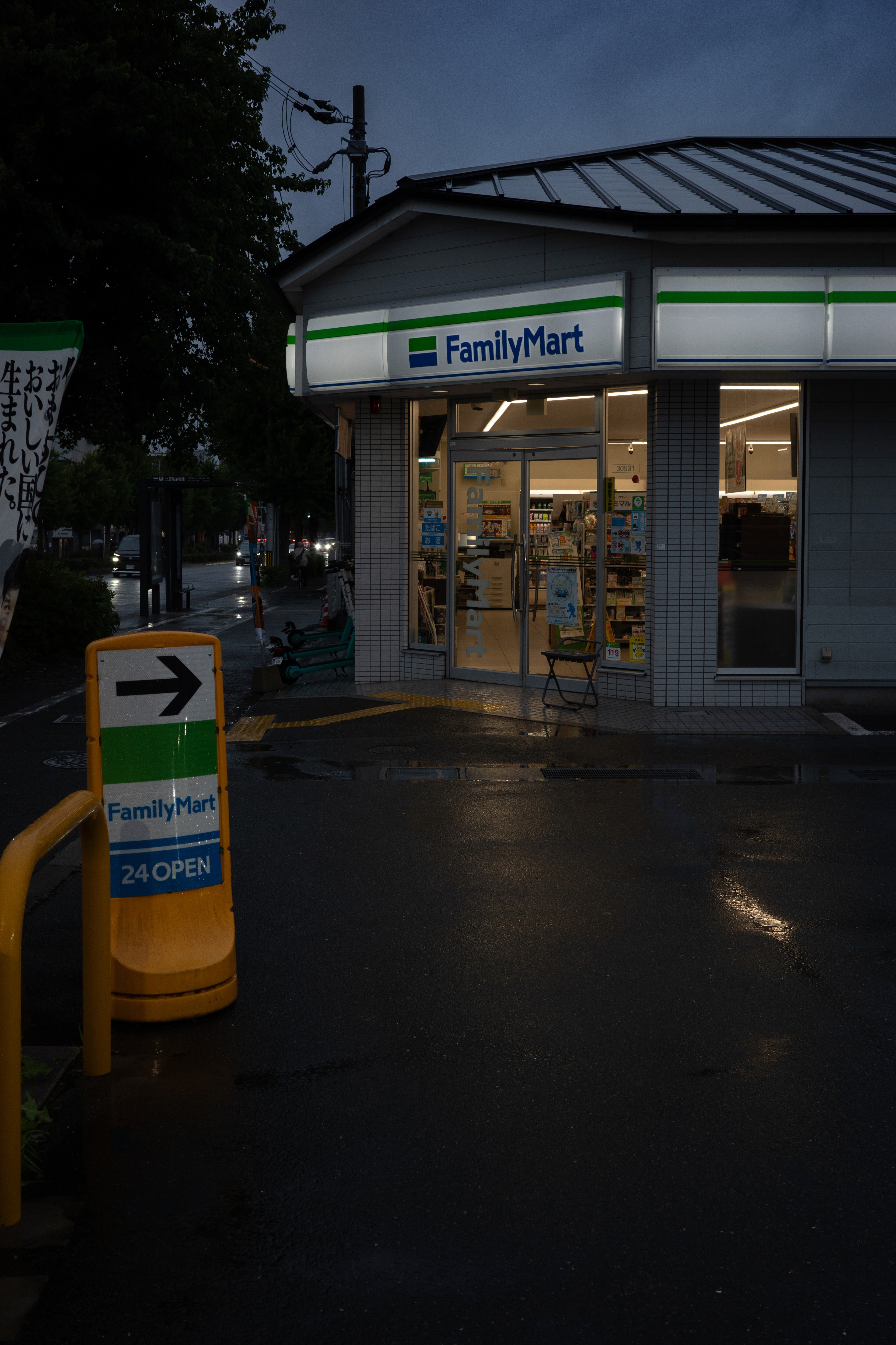 A convenience store glows at a rainy street corner.