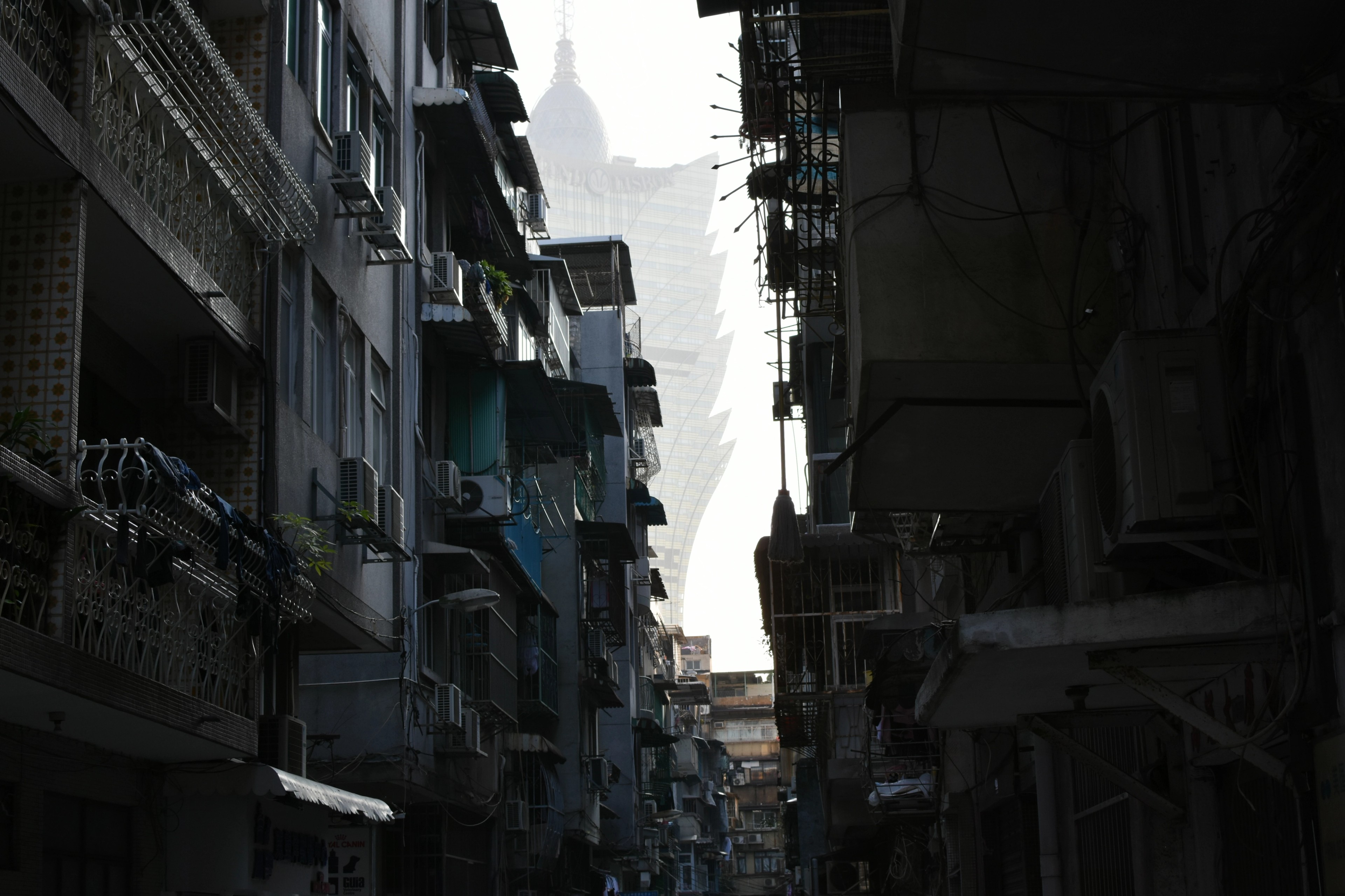 A narrow old Macau street beneath a cluster of modern towers.