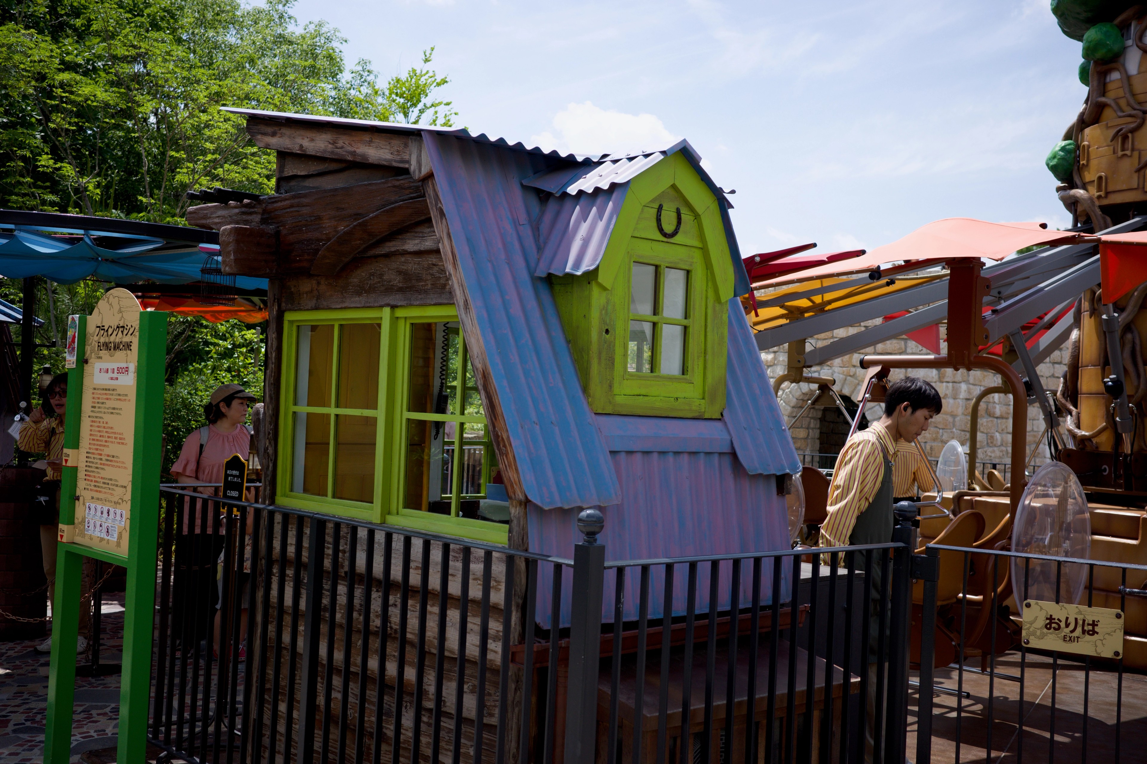 A brightly colored playhouse stands behind a low fence.