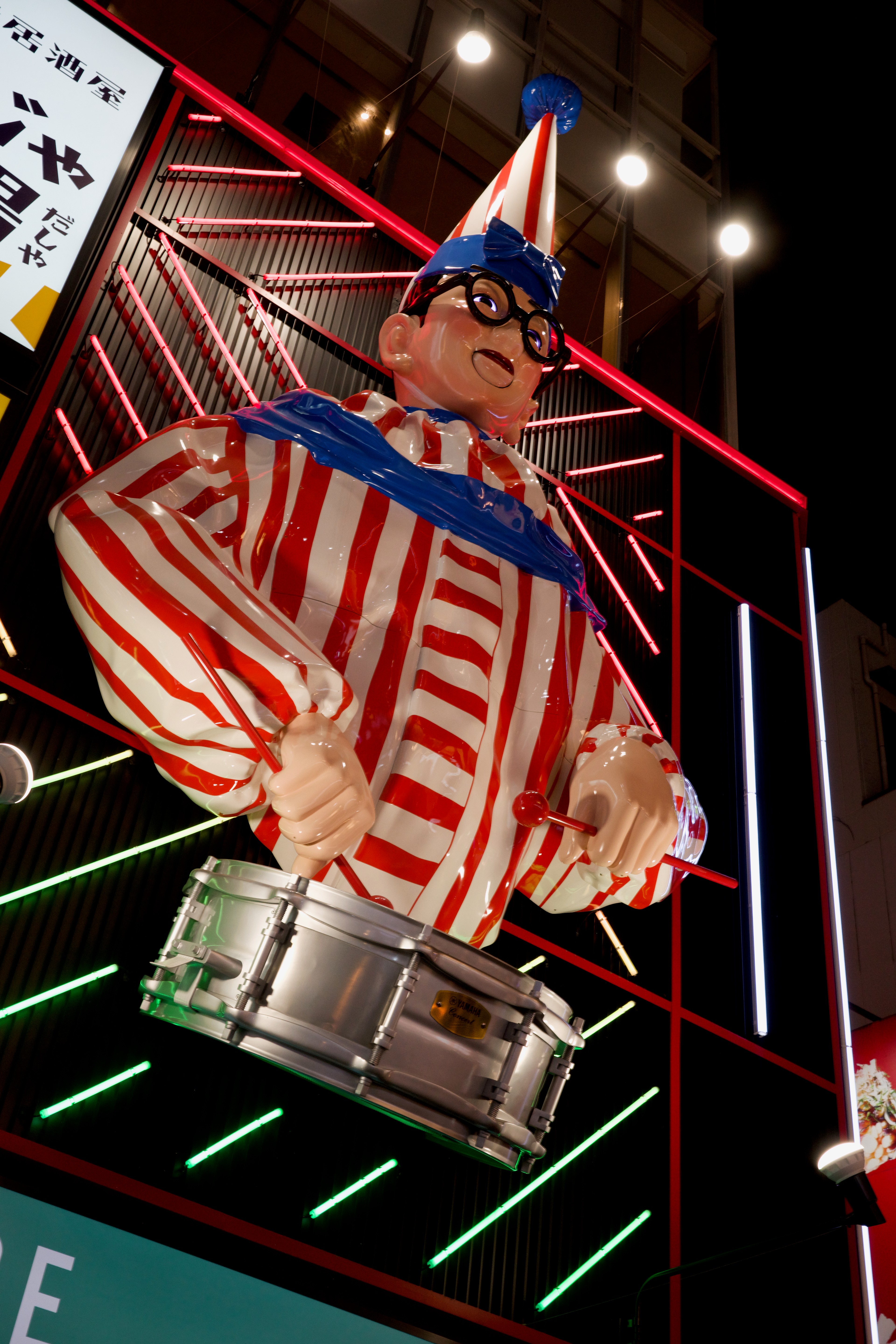 A brightly lit mechanical figure is mounted above the street.