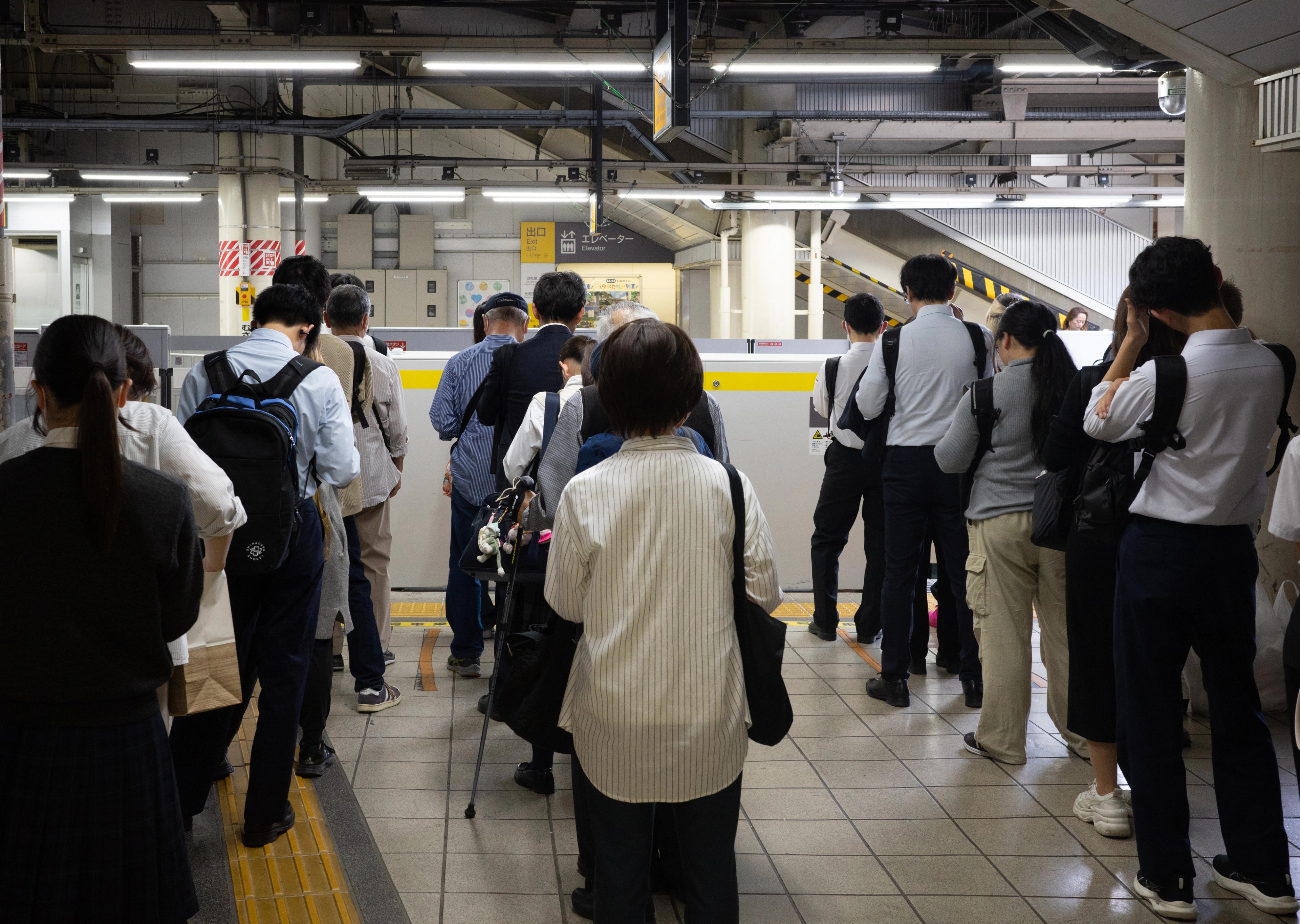 Commuters gather on a crowded station platform.