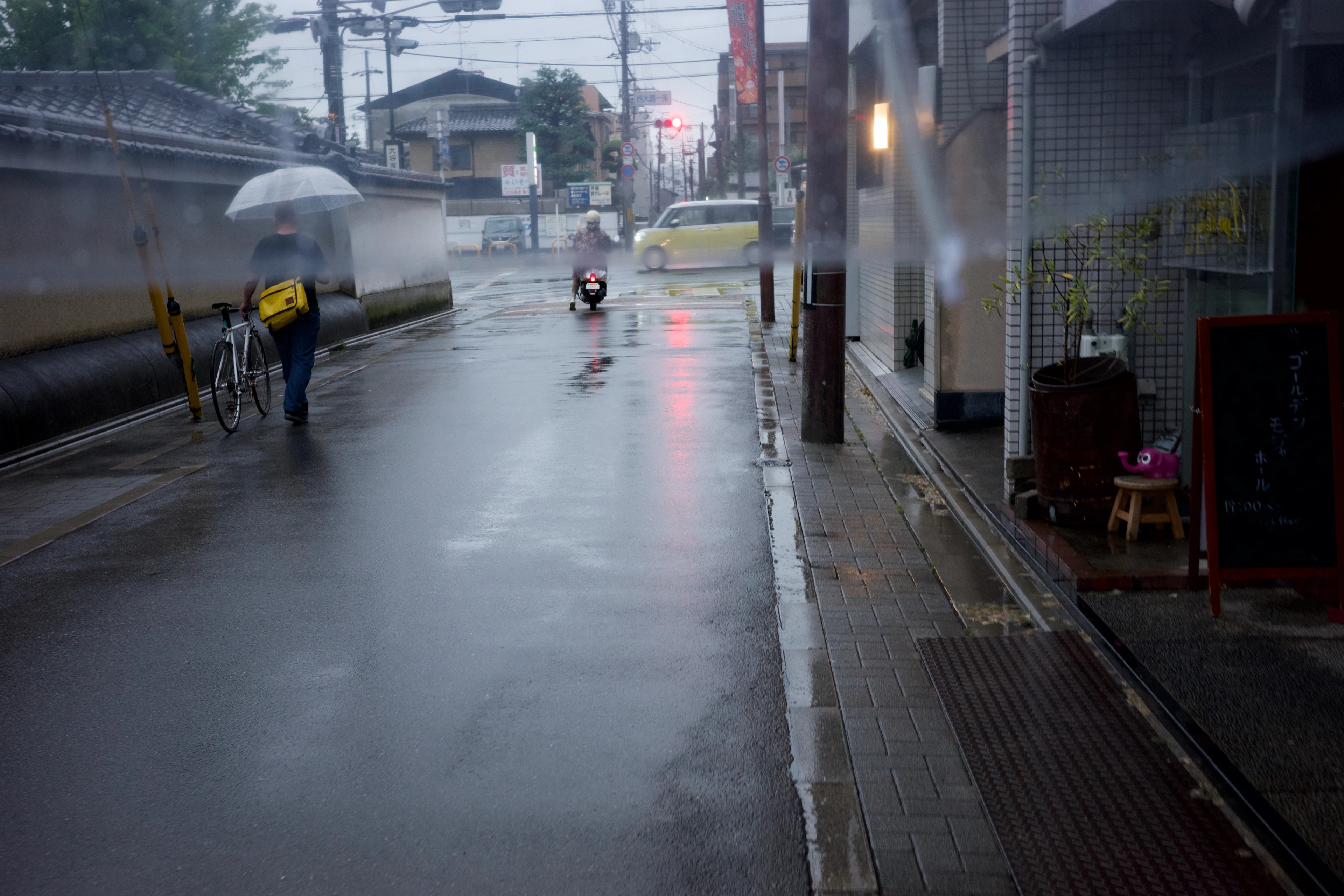 A rain-soaked street with an umbrella and bicycle.