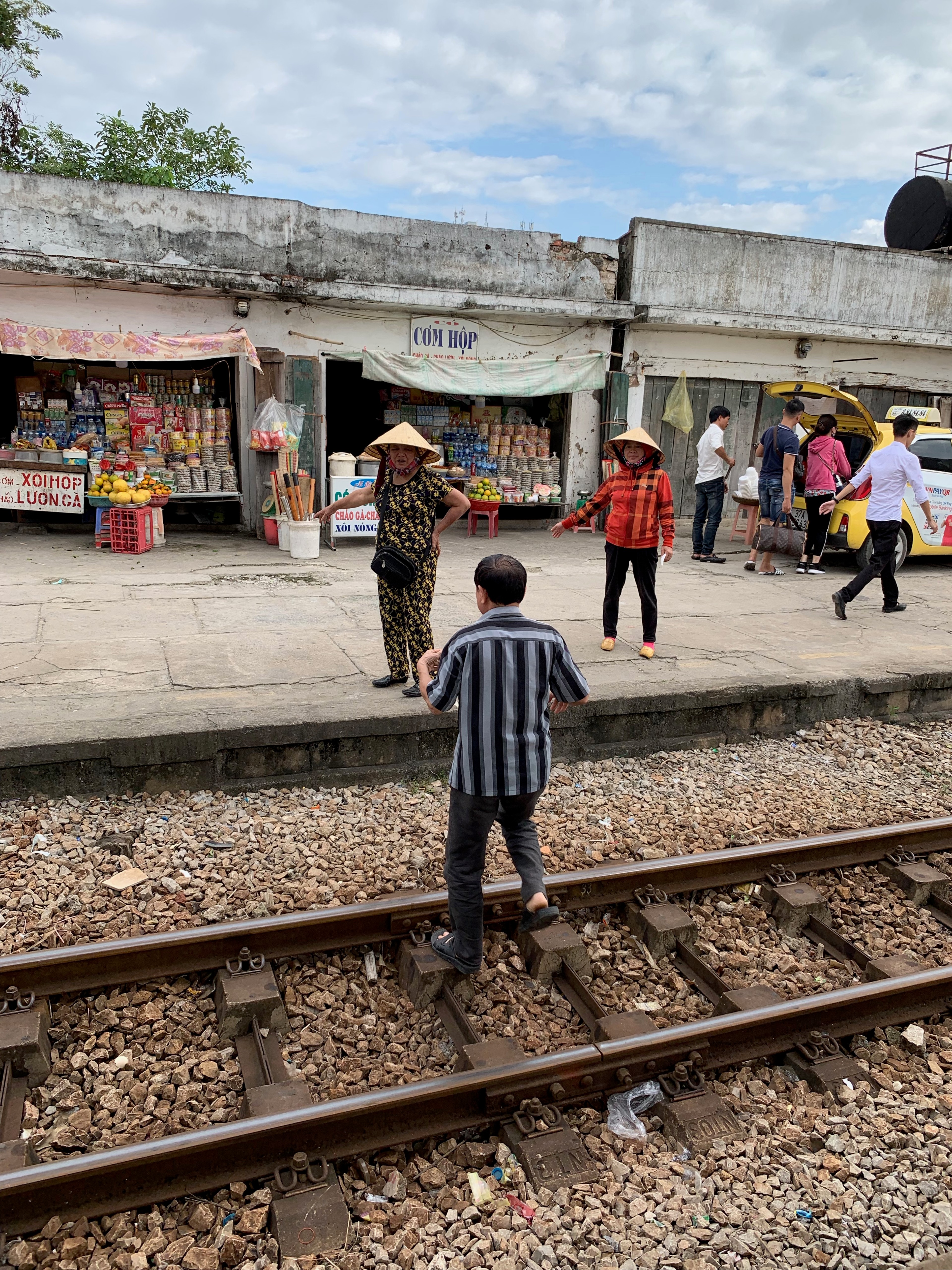 A man stands beside railway tracks near a small station platform.