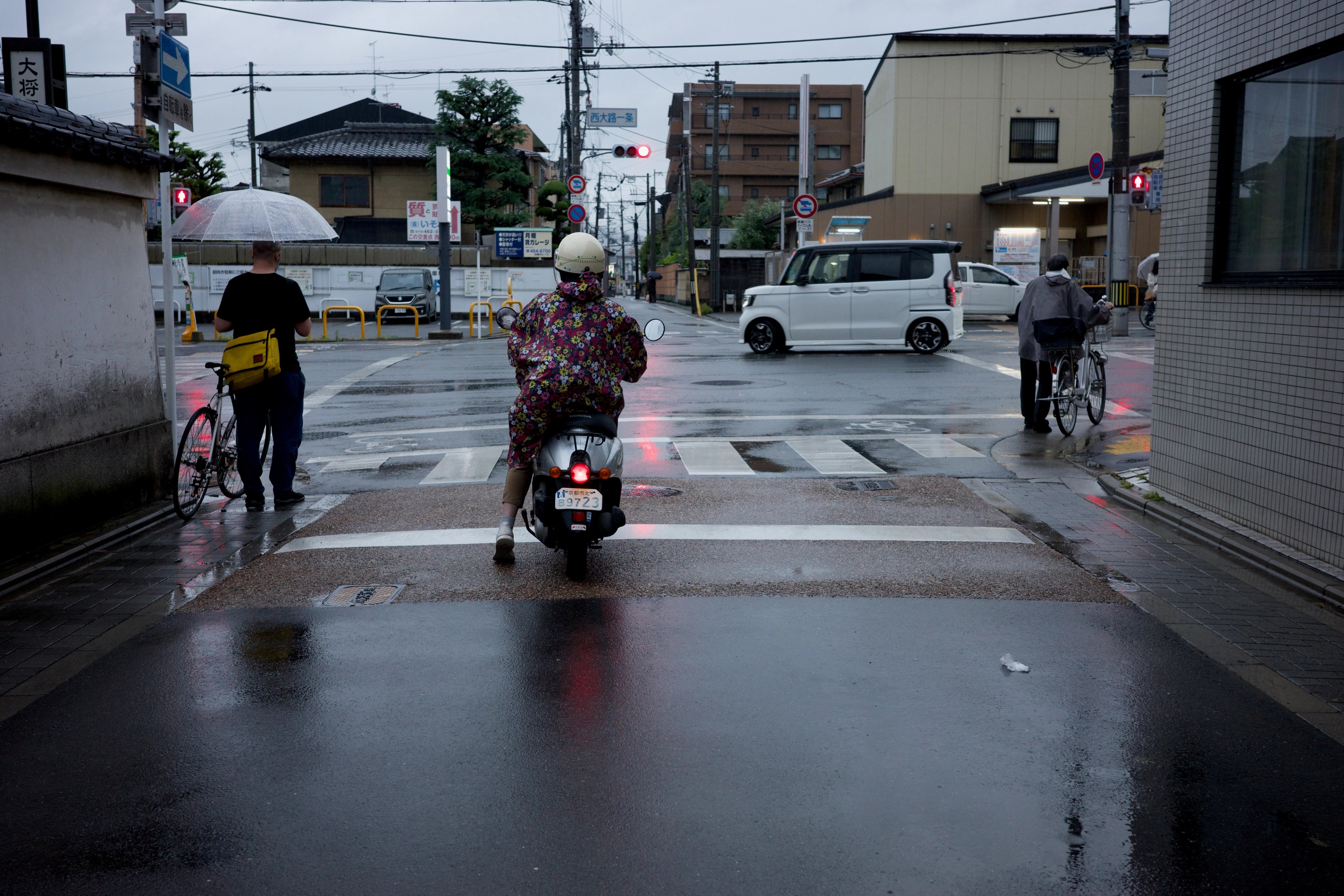 People ride through a wet intersection in the rain.