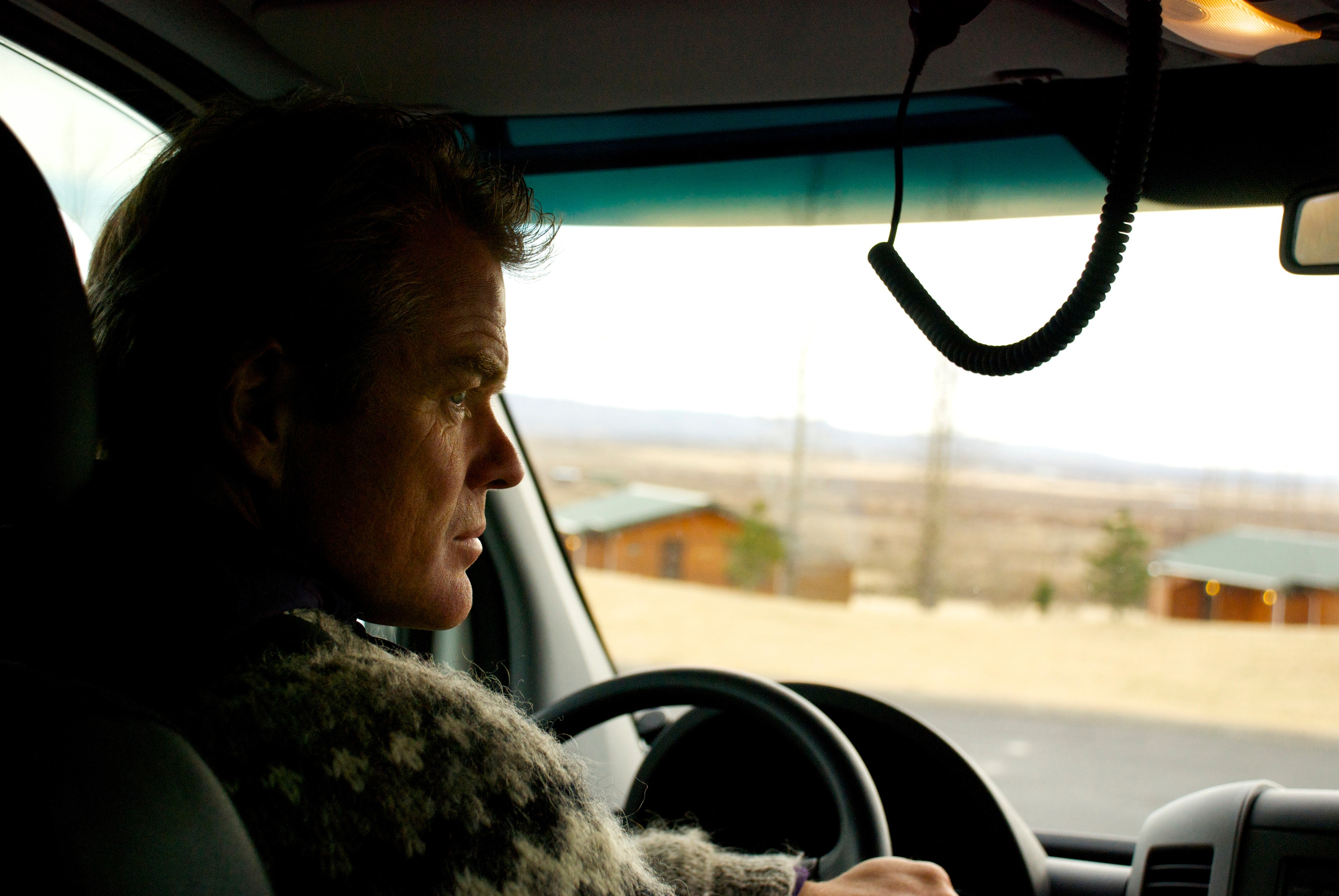 A driver looks ahead from the steering wheel of a vehicle.